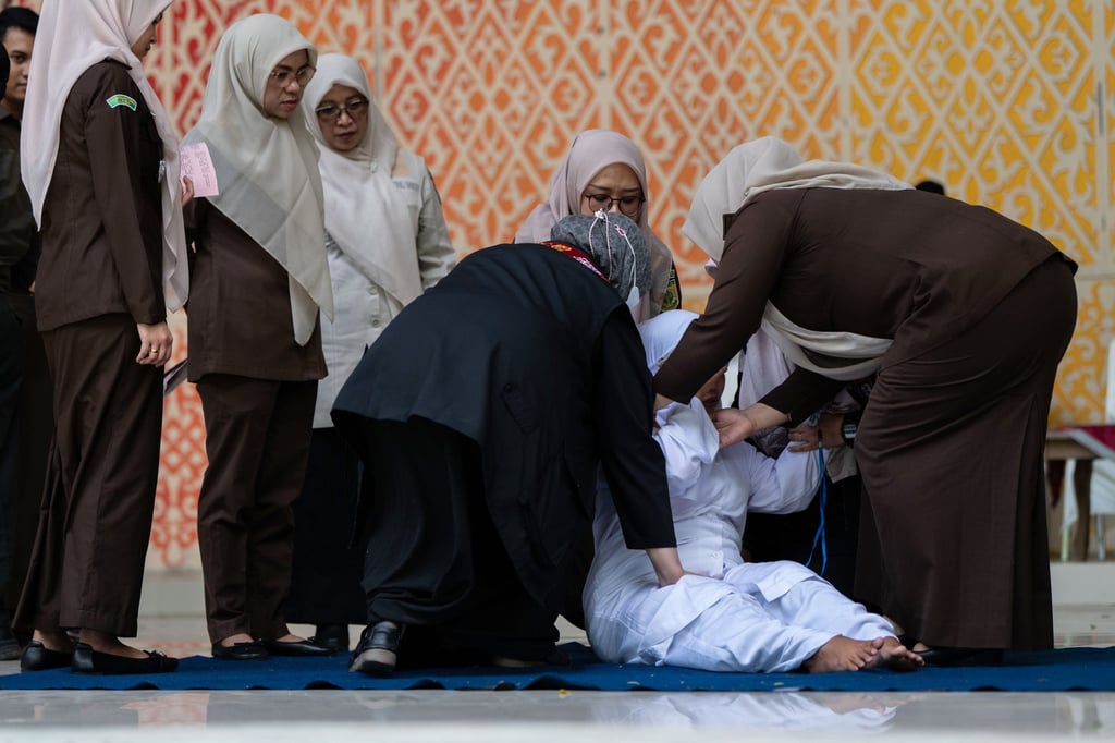 Officials help an unmarried woman get up after she was publicly caned for kissing during a TikTok livestream in Banda Aceh, Indonesia, on July 2. Photo: AP