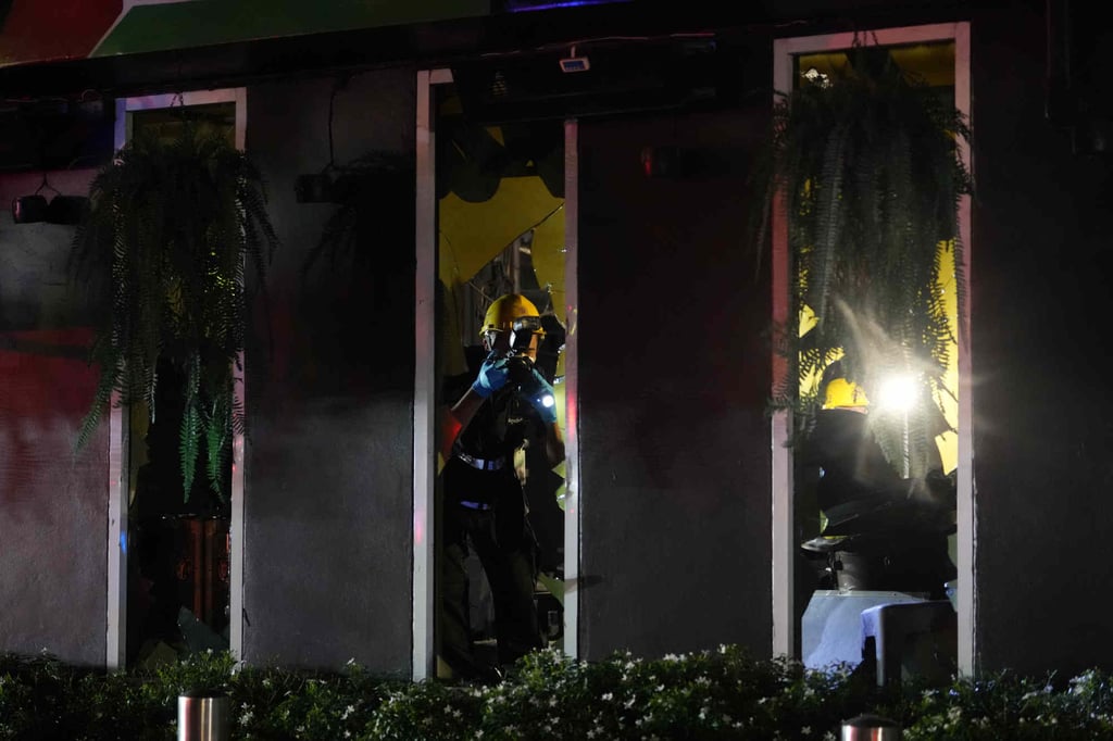 Forensic police officers inspect the site of a fire in Bangkok on Monday. Photo: AP