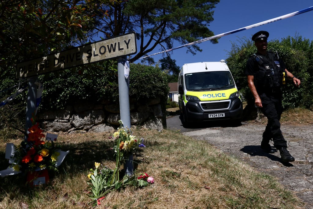 A police officer walks past flower tributes left outside the home of Ann Widdecombe in Haytor, Britain, on Saturday. Photo: Reuters