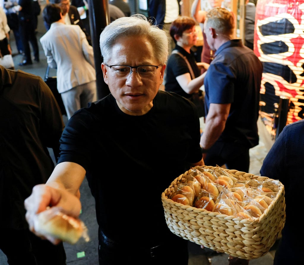 Nvidia CEO Jensen Huang hands out bread to journalists in front of a restaurant during a dinner in Tokyo on Wednesday. Photo: Reuters