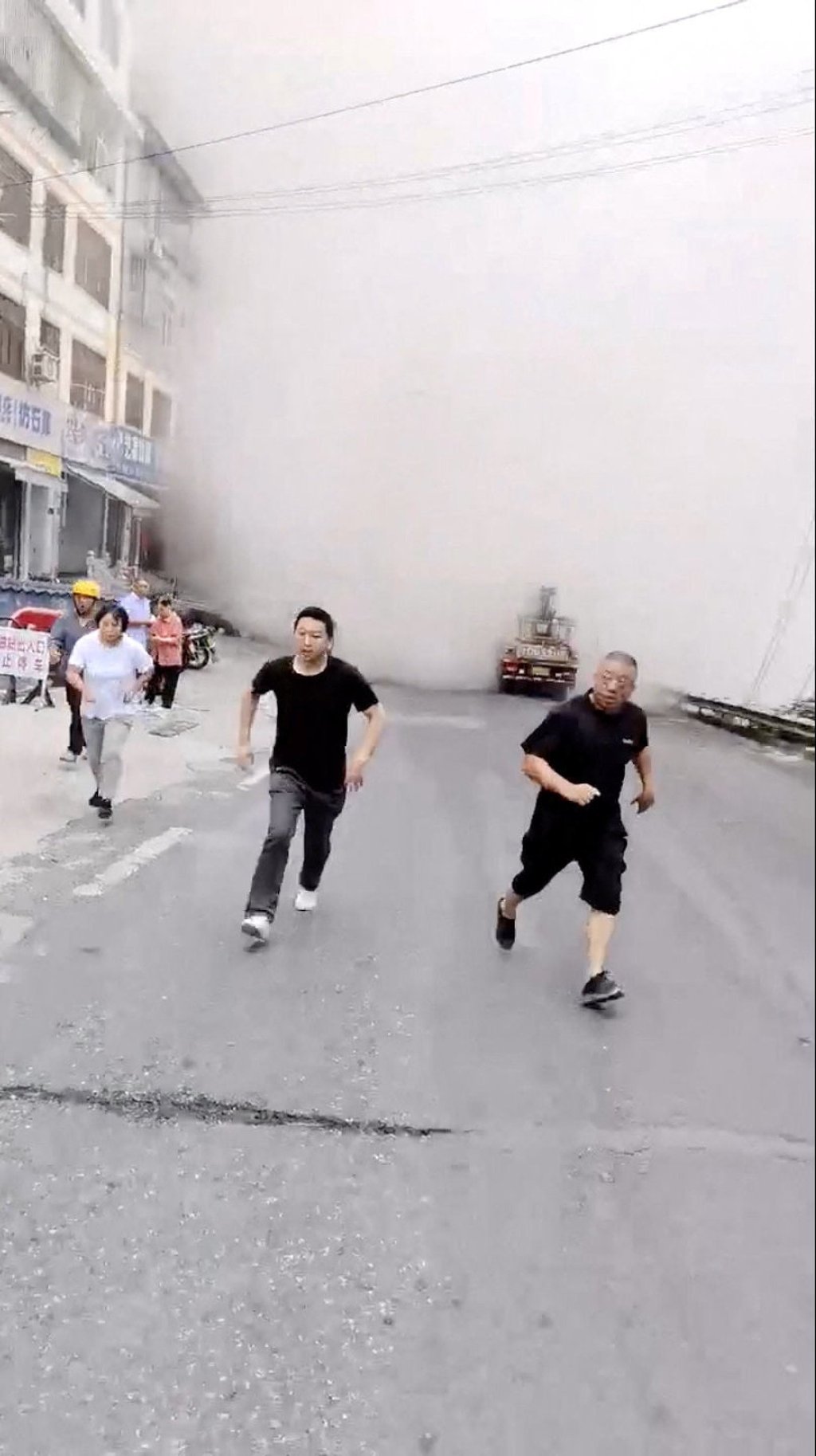 A social media video taken in Chongqing shows people away from a cloud of dust rising as buildings collapse due to a landslide. Photo: social media via Reuters