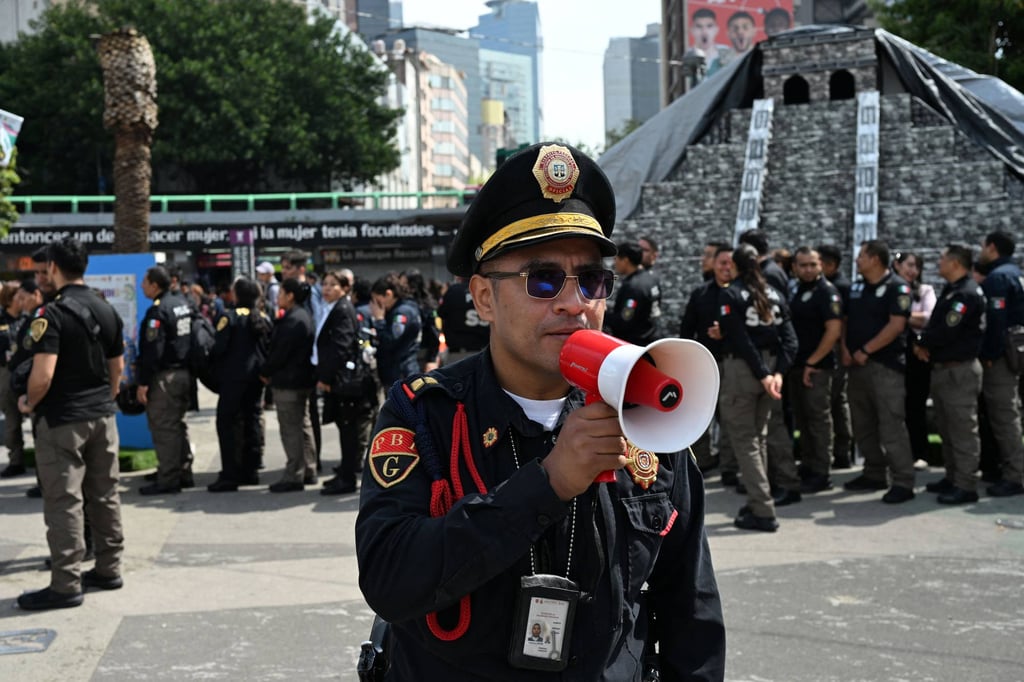 A member of the Secretariat of Citizen Security uses a megaphone to give instructions to personnel evacuated from several buildings in Mexico City after an earthquake on Friday. Photo: AFP