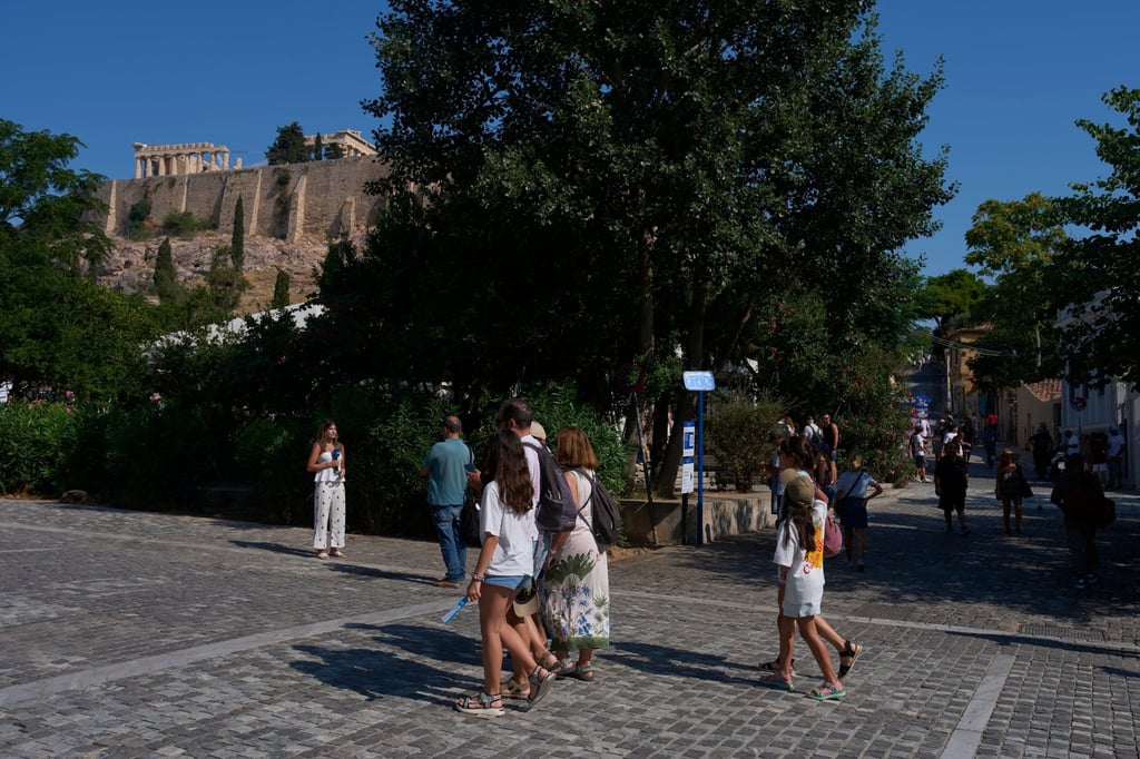 Tourists walk near the Acropolis in Athens on Tuesday after two tourists were stabbed and injured nearby in an attack near the entrance to the archaeological site. Photo: AP