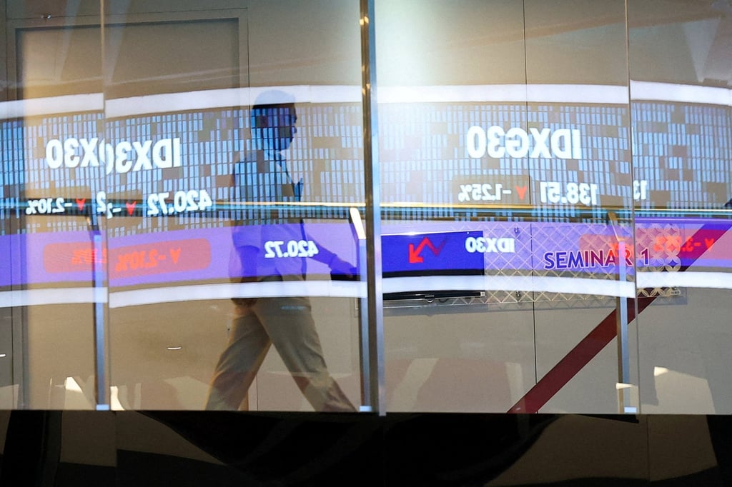 A man walks past a glass window reflecting an electronic sign showing the stock market index at the Indonesia Stock Exchange in Jakarta. Photo: Reuters