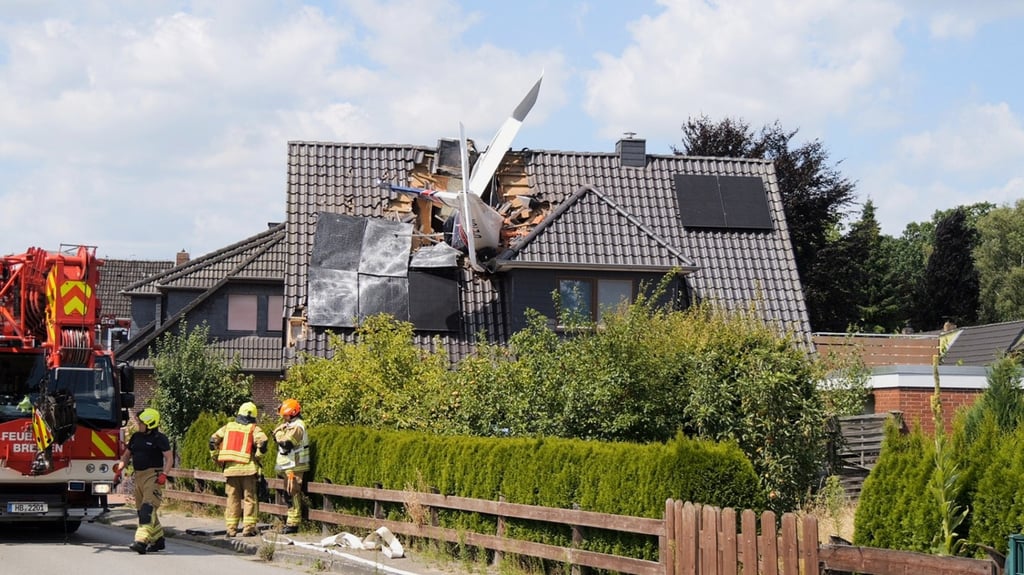 Emergency services at the scene after a small plane crashed lodged in the roof of a house, in Ganderkesee, Germany, on Saturday. Photo: dpa via AP