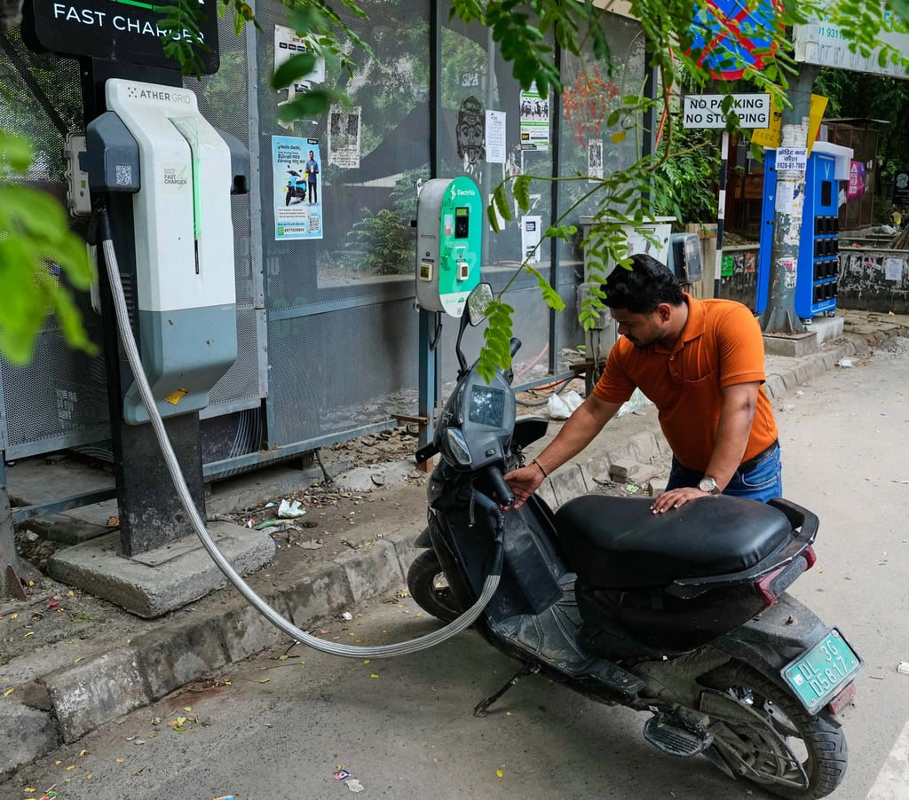 A man charges his electric scooter at a roadside station in Delhi on July 13. Photo: AP