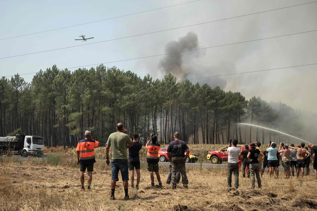 Volunteers and bystanders watch as firefighters tackle a forest fire in Lanton, southwestern France on Wednesday. Photo: AFP