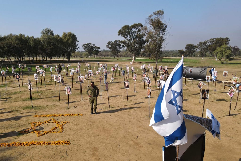 Israeli soldiers in December 2023 walk among photos of people taken captive or killed by Hamas militants during a music festival on October 7 that year, at the site where the massacre took place. Photo: AFP