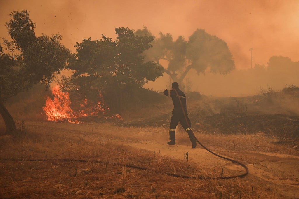 A fireman runs to extinguish a fire in an olive grove in the settlement of Zachouli, Greece, on Sunday. Photo: Reuters