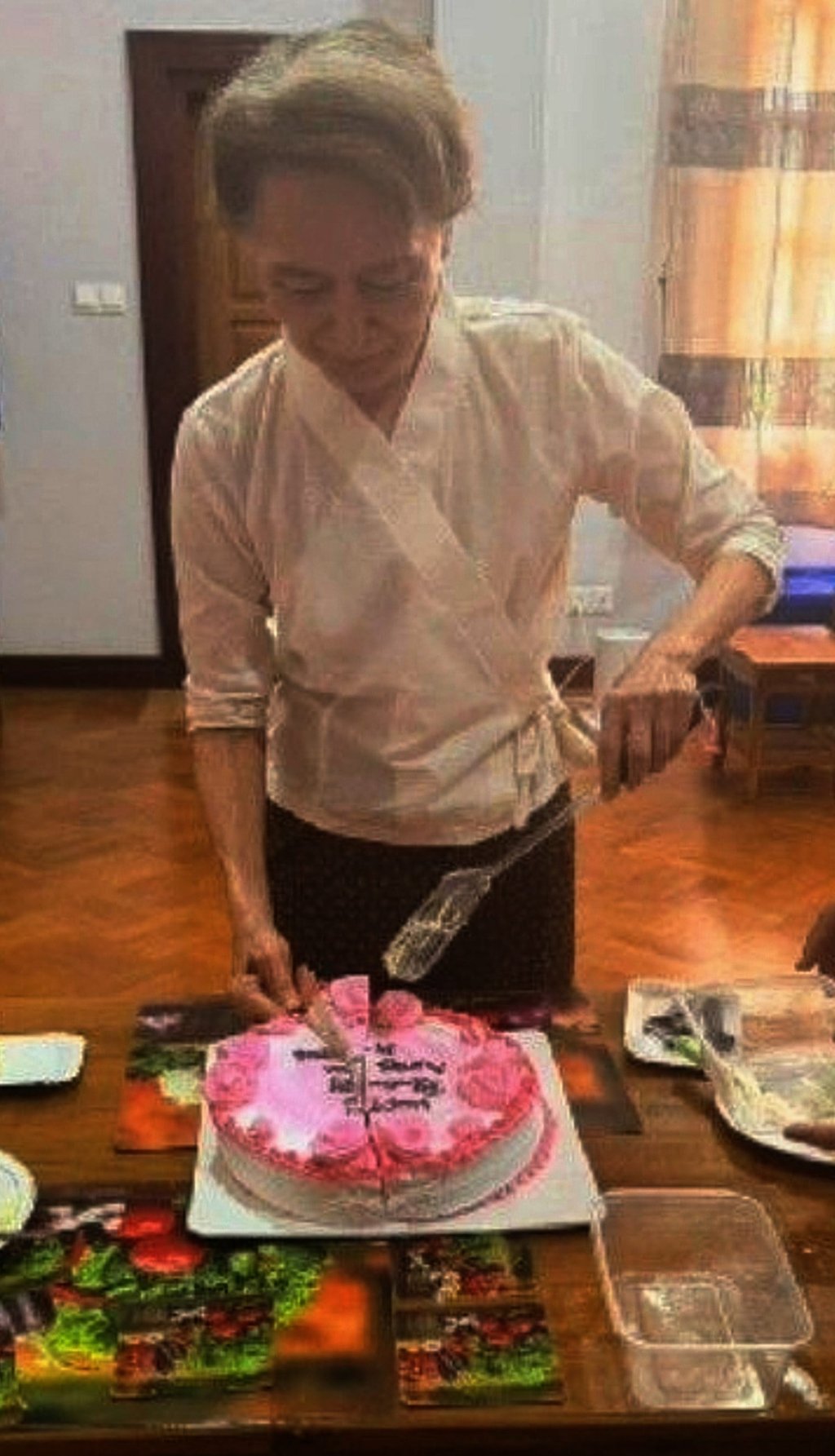 Myanmar ousted leader Aung San Suu Kyi cuts a birthday cake during her meeting with Arnaud de Baecque on Monday. Photo: Myanmar President Office/AP