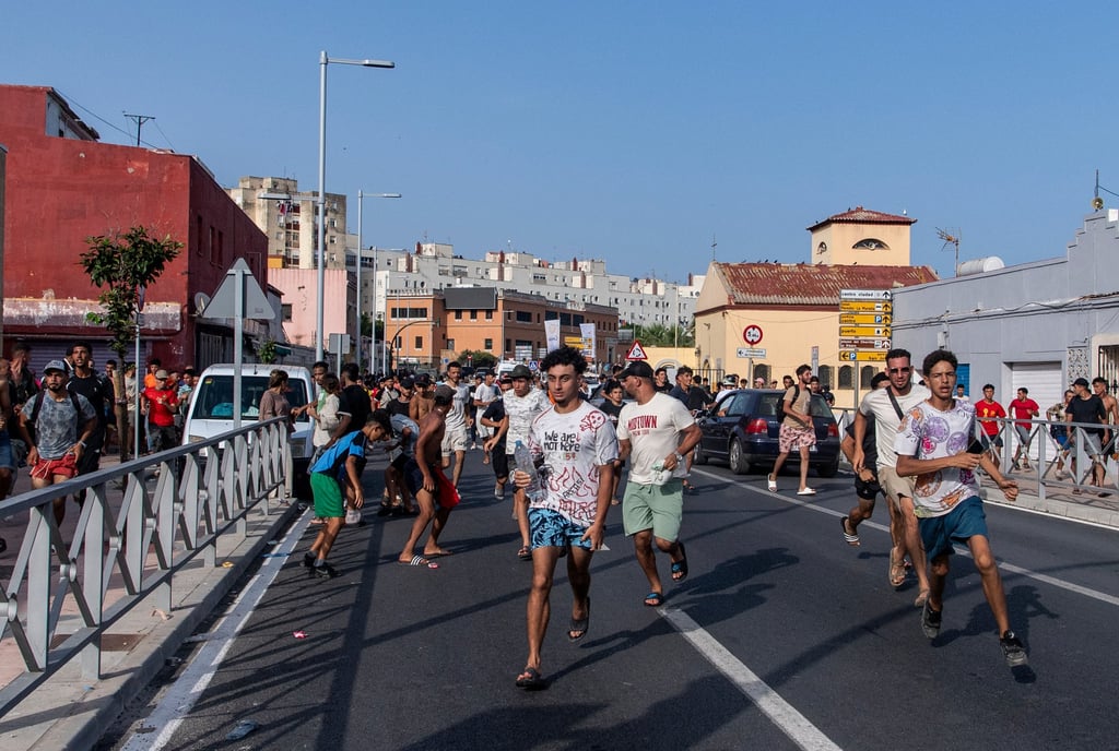 Migrants run from Spanish police after crossing from Morocco into Ceuta on Friday. Photo: AP