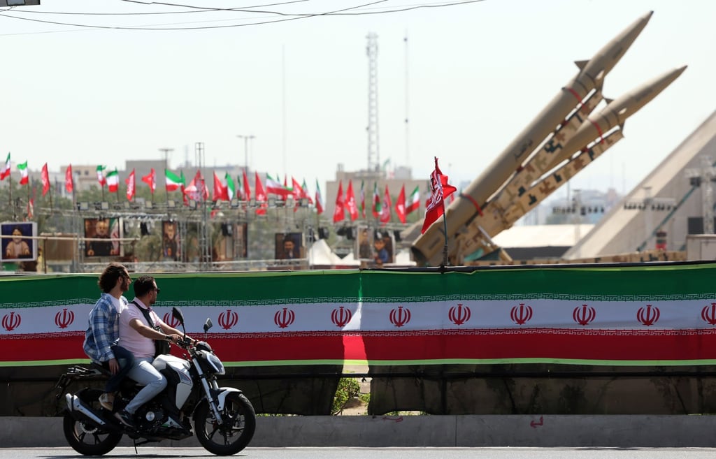 Motorcyclists drive past Iranian missiles on display above a banner depicting US President Trump at Azadi Square in Tehran on July 30. Photo: EPA