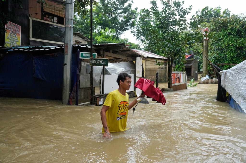 A man walks through floodwater caused at Bagong Silagan village in Quezon City, Metro Manila, Philippines. Photo: AP