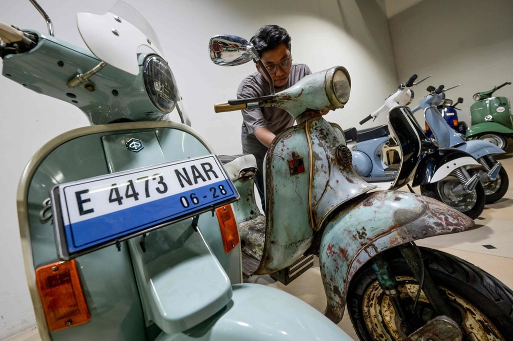 A worker inspects a Vespa that has been converted to an electric scooter at a workshop in Jakarta in 2025. Photo: AFP