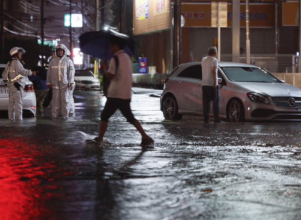 A person wades through a flooded road in Chiba prefecture, Japan, on Thursday. Photo: Kyodo