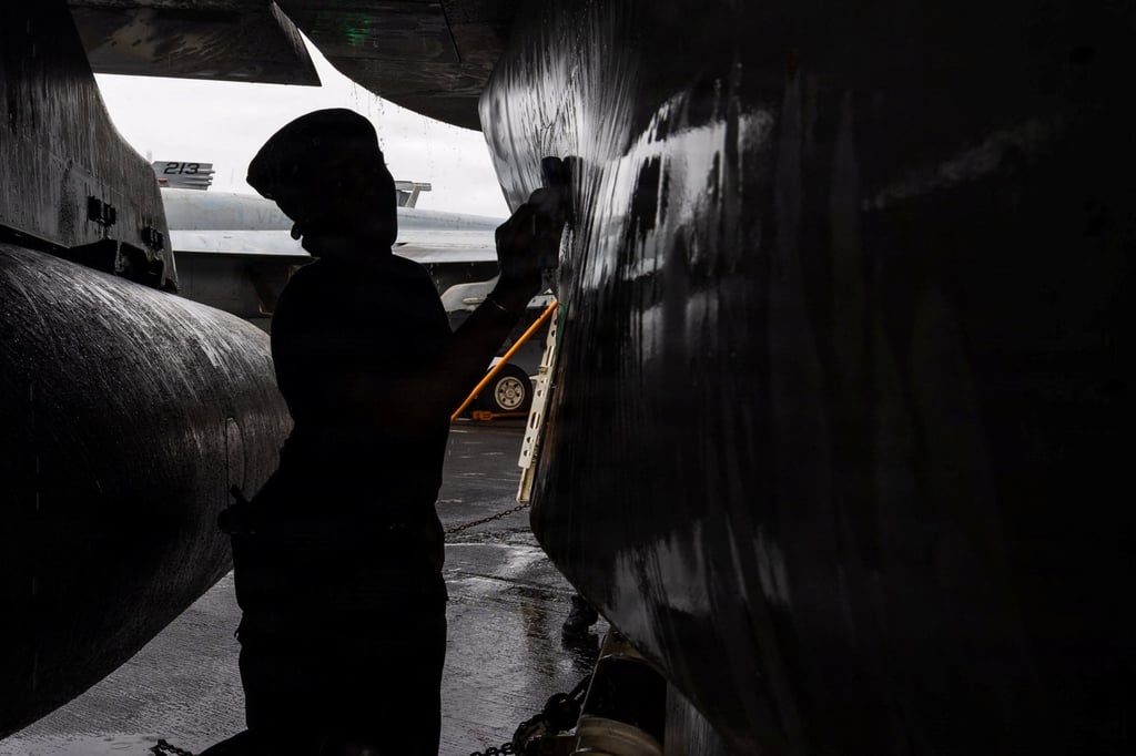 A US sailor scrubs an EA-18G Growler on the flight deck of the USS Abraham Lincoln on Sunday. Photo: US Navy via Reuters