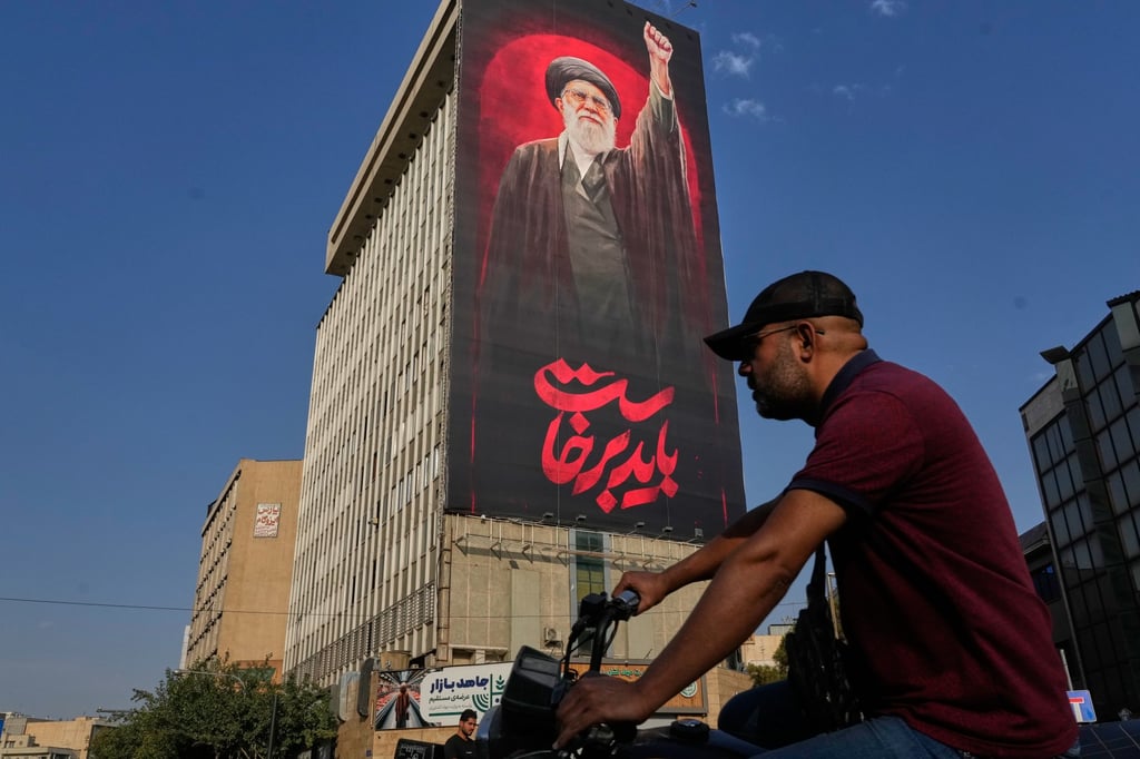 A man rides past a billboard with a message that reads in Farsi: “We must rise up” and an image of the late Iranian supreme leader Ayatollah Ali Khamenei, in Tehran, on Saturday. Photo: AP