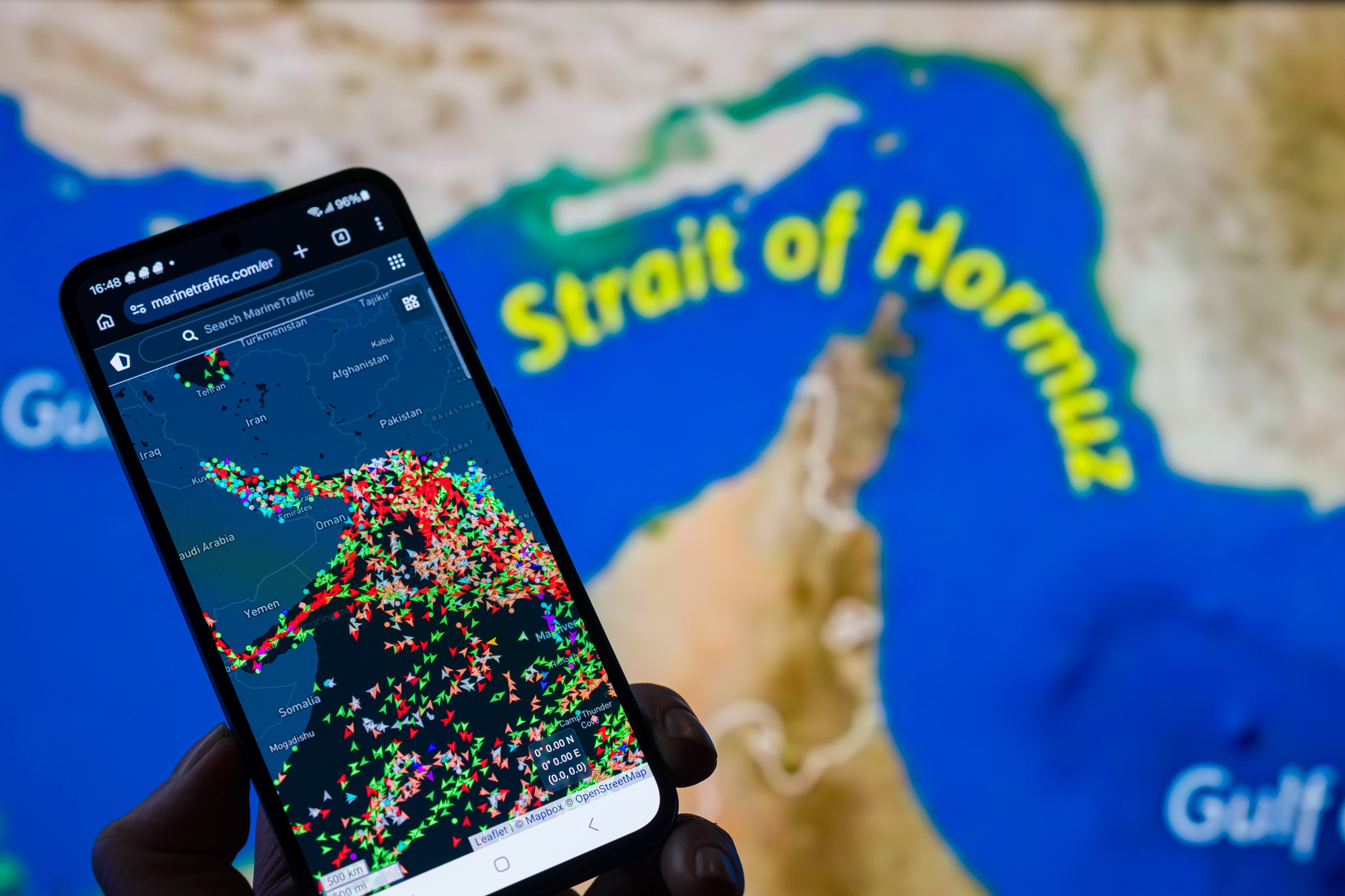 A MarineTraffic map showing ship movements in the Strait of Hormuz is displayed on a smartphone screen with a map in the background, in Brussels, Belgium, on March 15. Photo: Getty