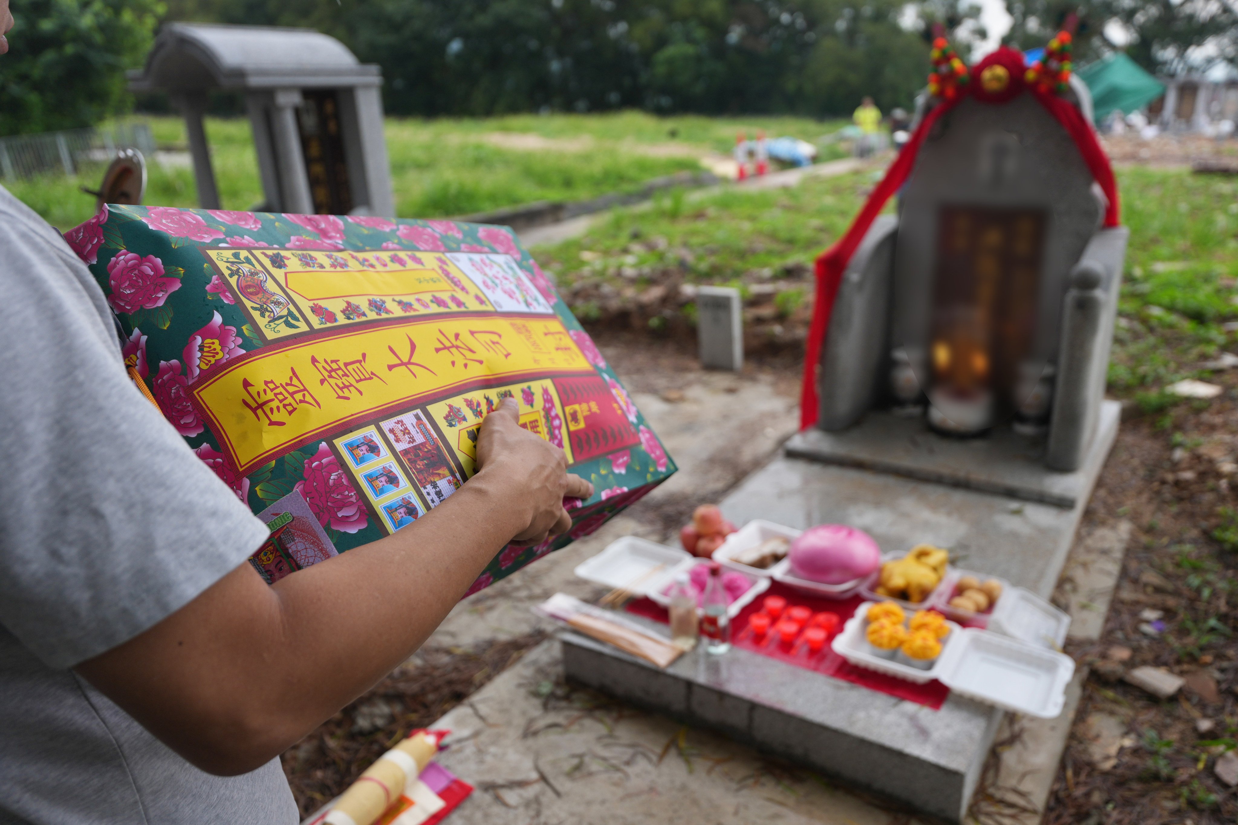 (Words on grave is blurred) Family members pay tribute to a victim of the Wang Fuk Court fire. Photo: Karma Lo