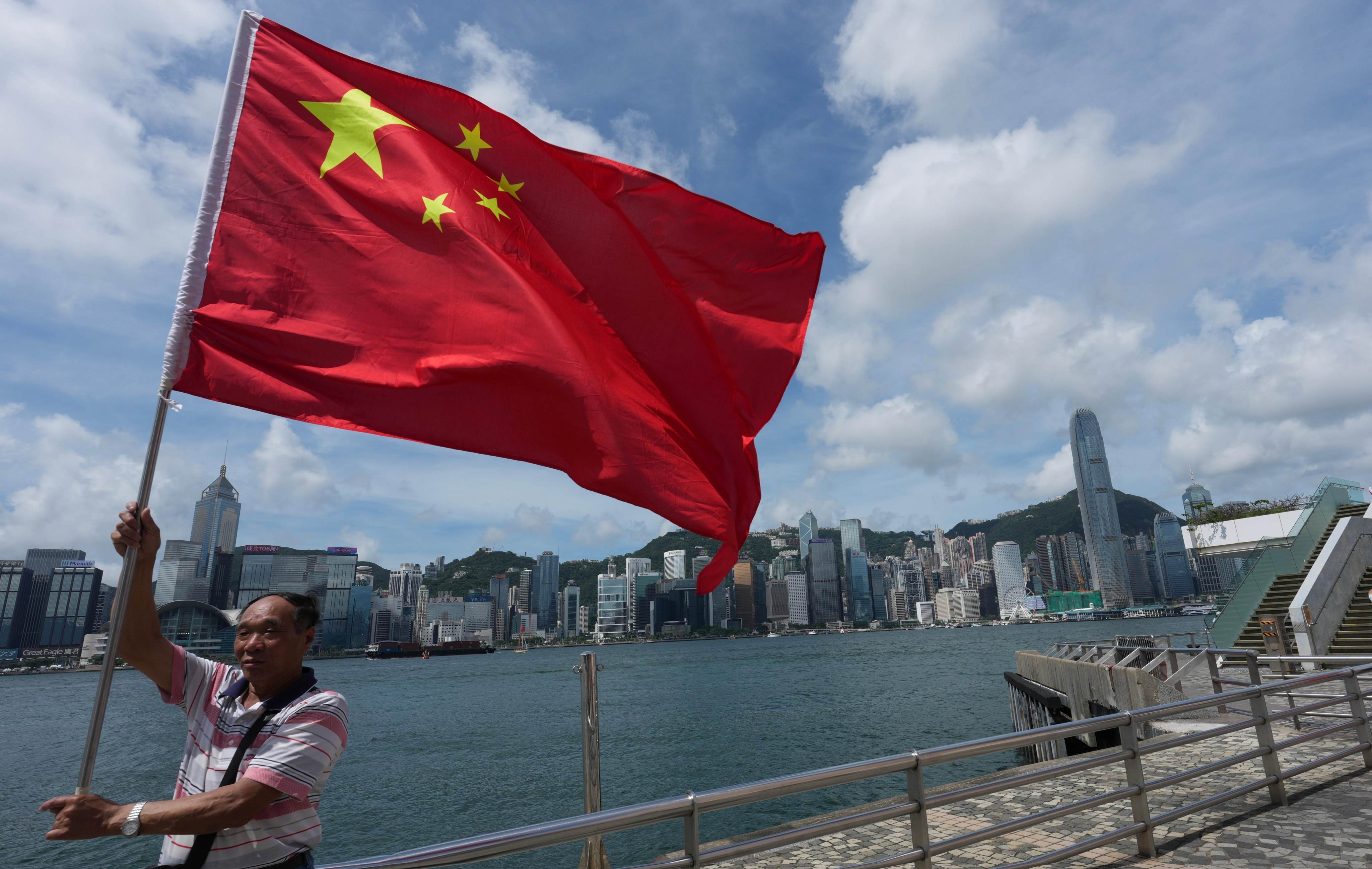A man holds a national flag at the Tsim Sha Tsui waterfront on the anniversary of Hong Kong’s return to Chinese rule. Photo: Jelly Tse