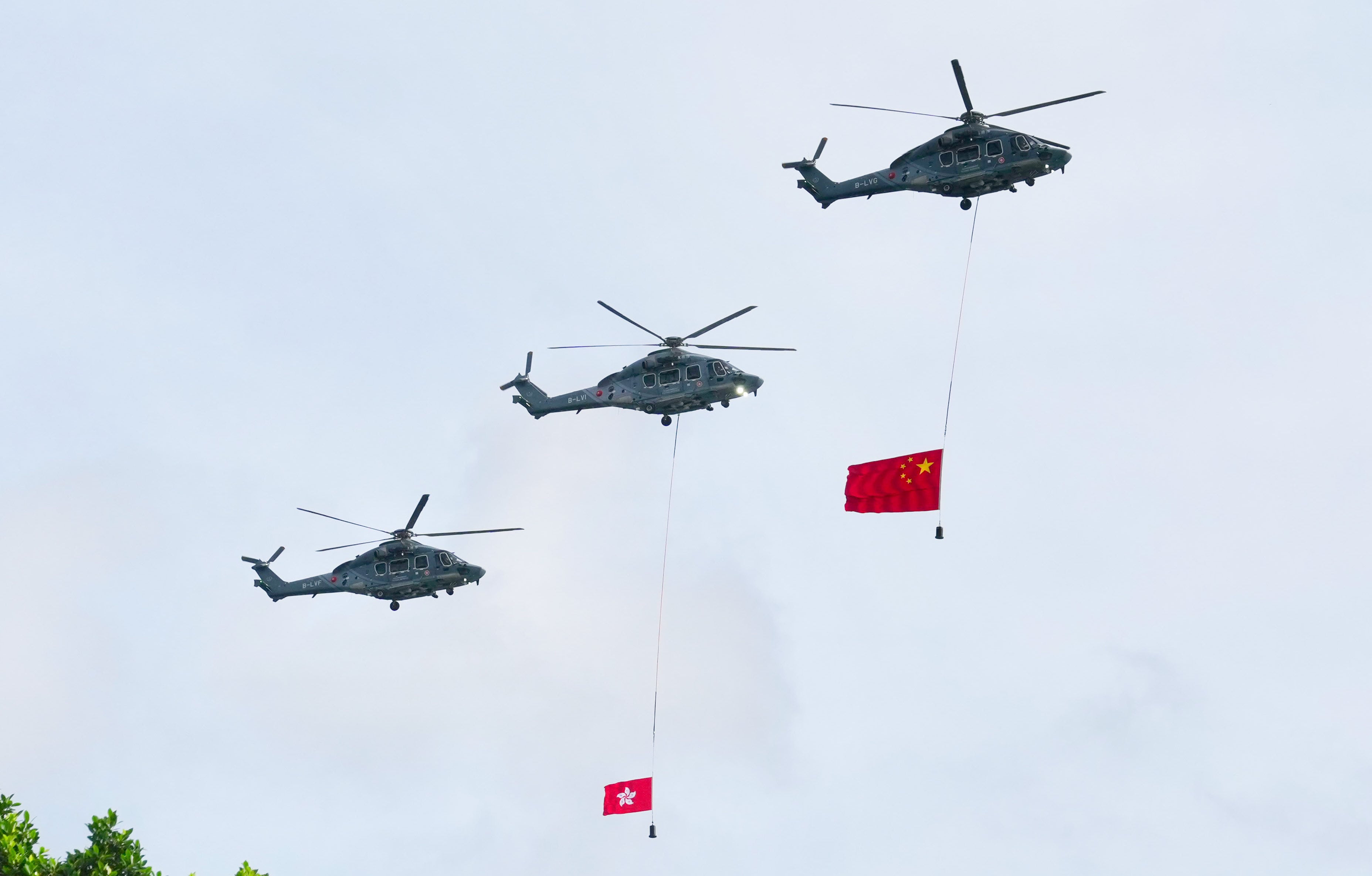 Helicopters fly past carrying Chinese and Hong Kong flags. Photo: Karma Lo
