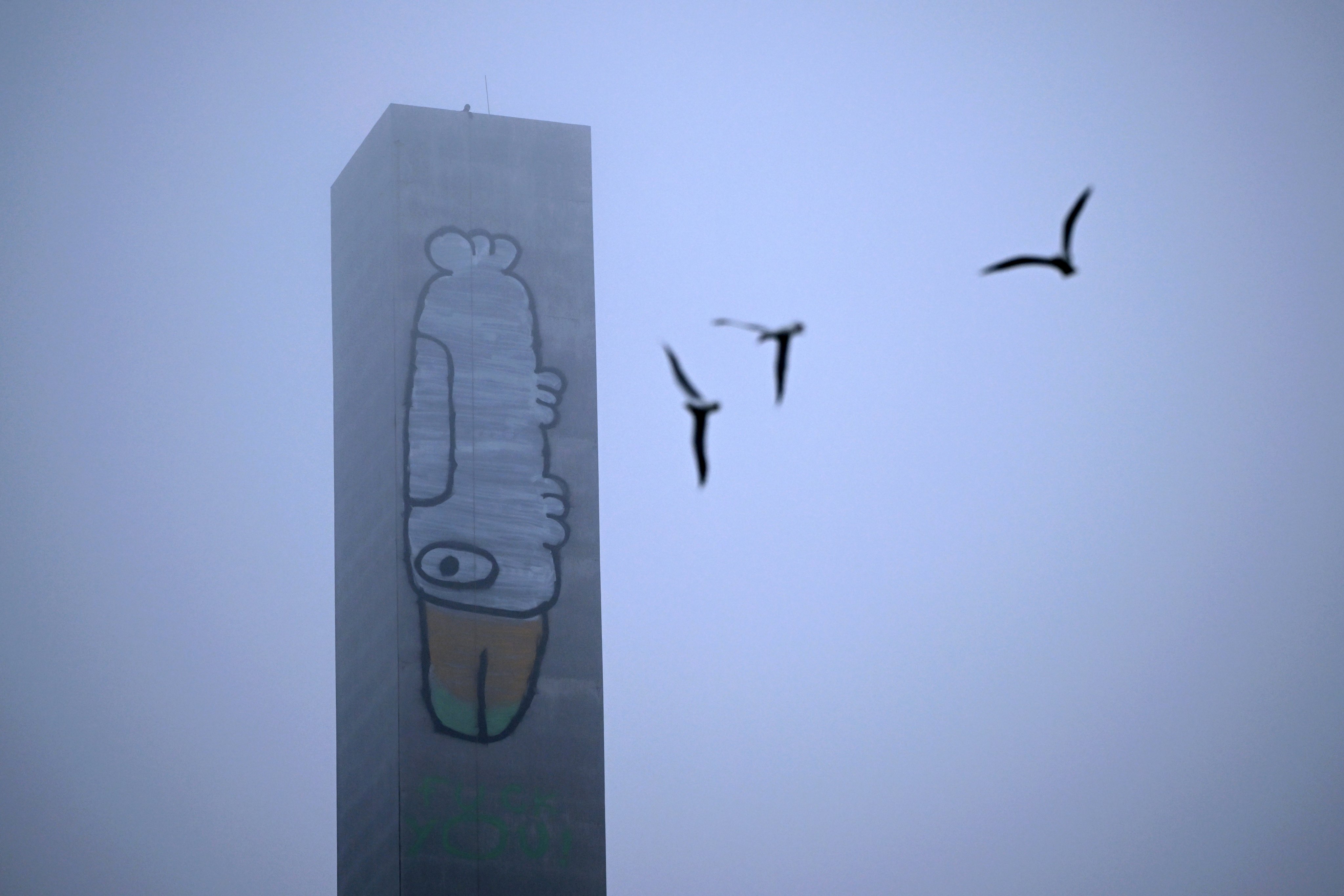 A man stands on top of the graffitied eastern pylon of the Bolte Bridge in Melbourne on Tuesday. Photo: EPA