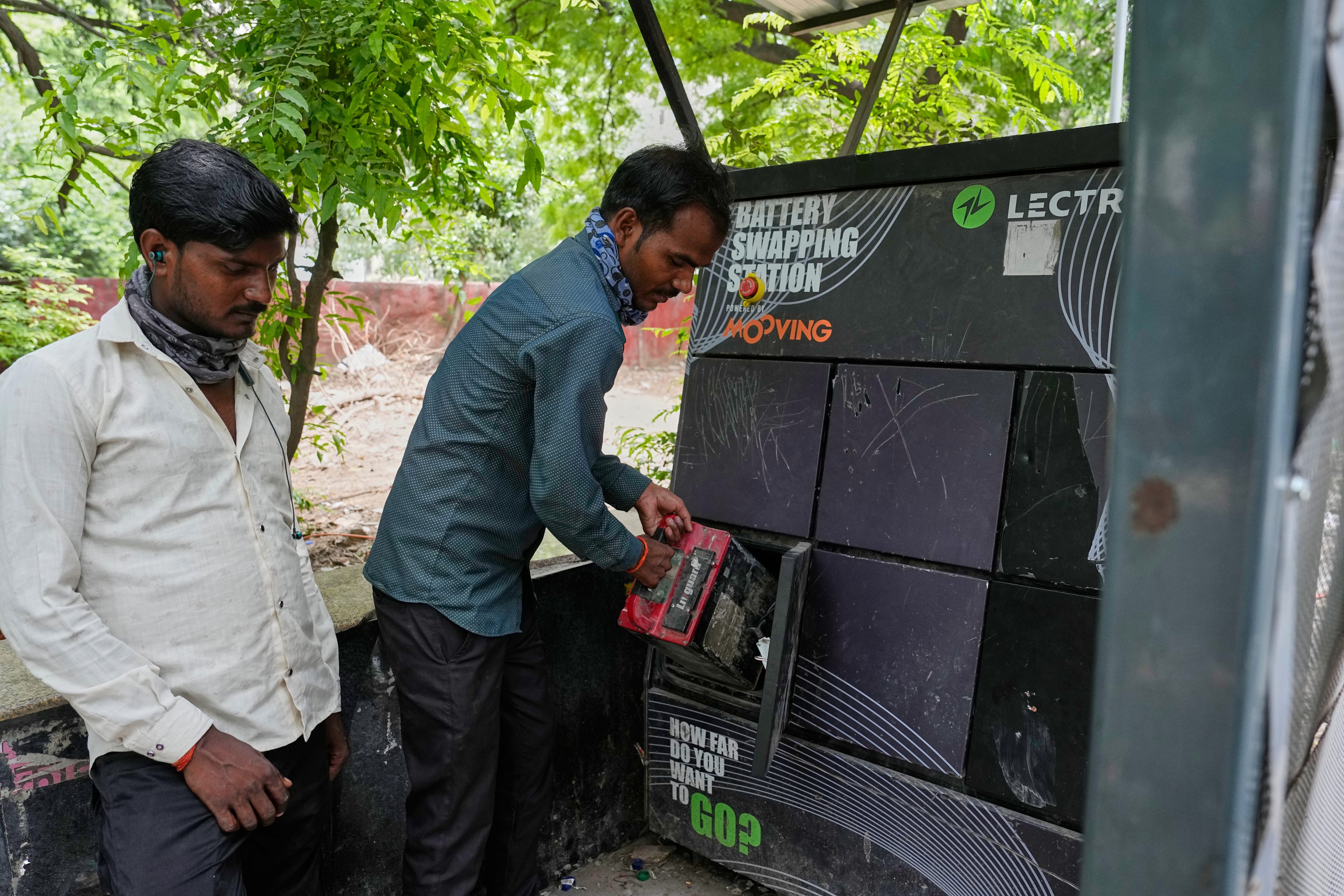 A man swaps his electric scooter battery at a station for electric vehicles in Delhi on July 13. Photo: AP