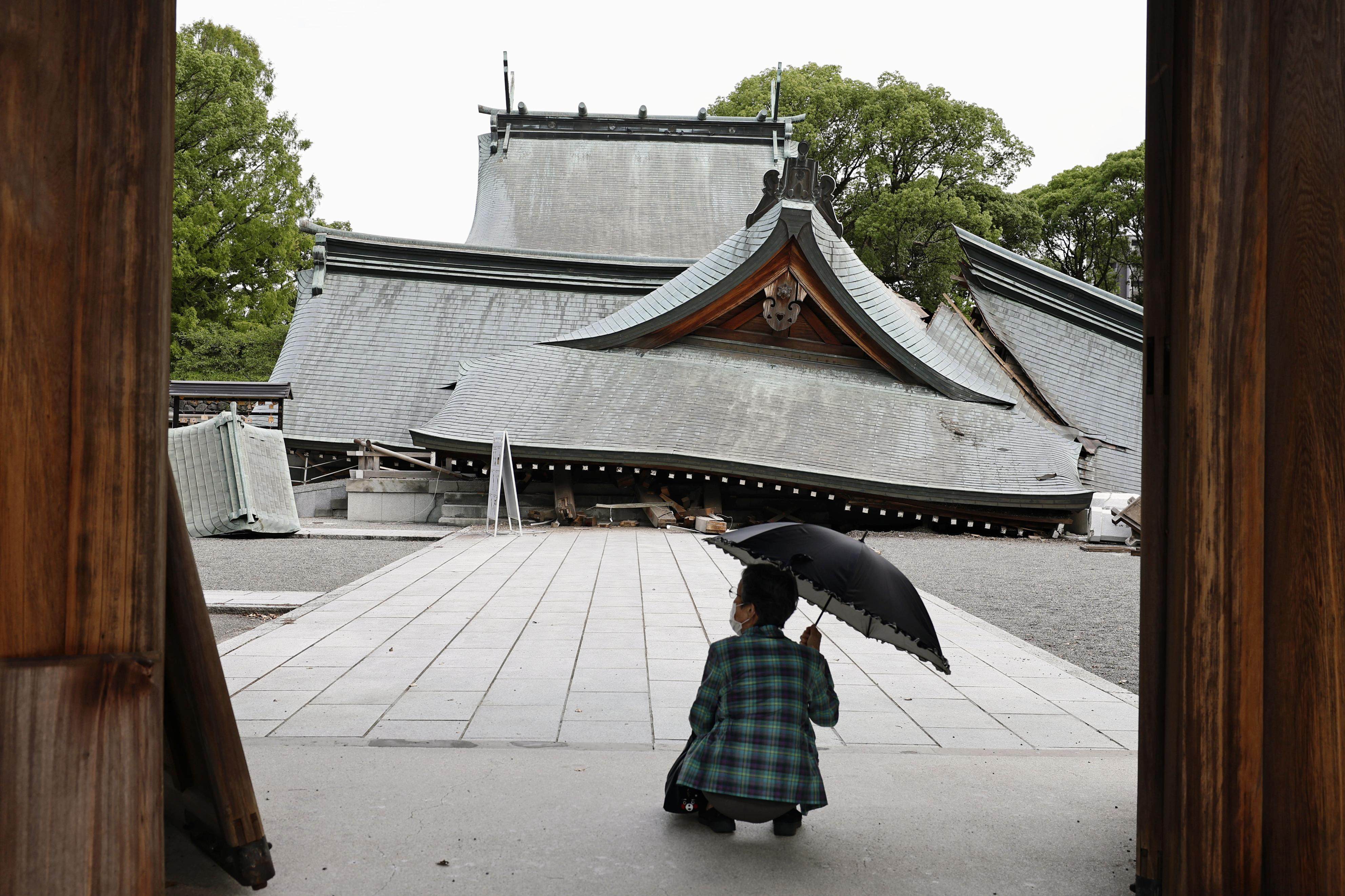 A visitor looks at the fallen roofs of the Yatsuhiro Shrine, a day after the quake. Photo: Kyodo News via AP