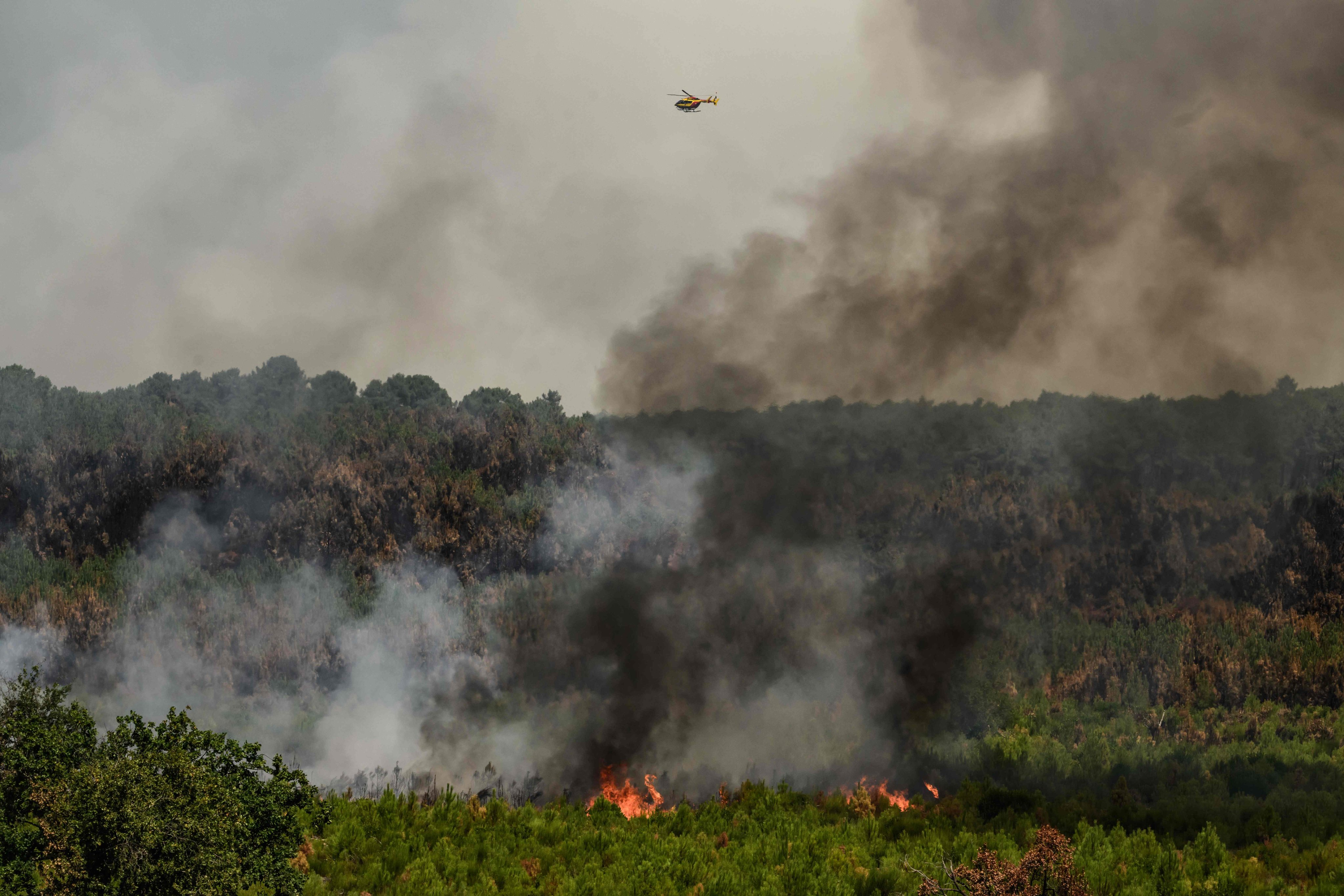 A helicopter flies over smoke rising from a forest fire outside Lege-Cap-Ferret, southwestern France, on Tuesday. Photo: AFP