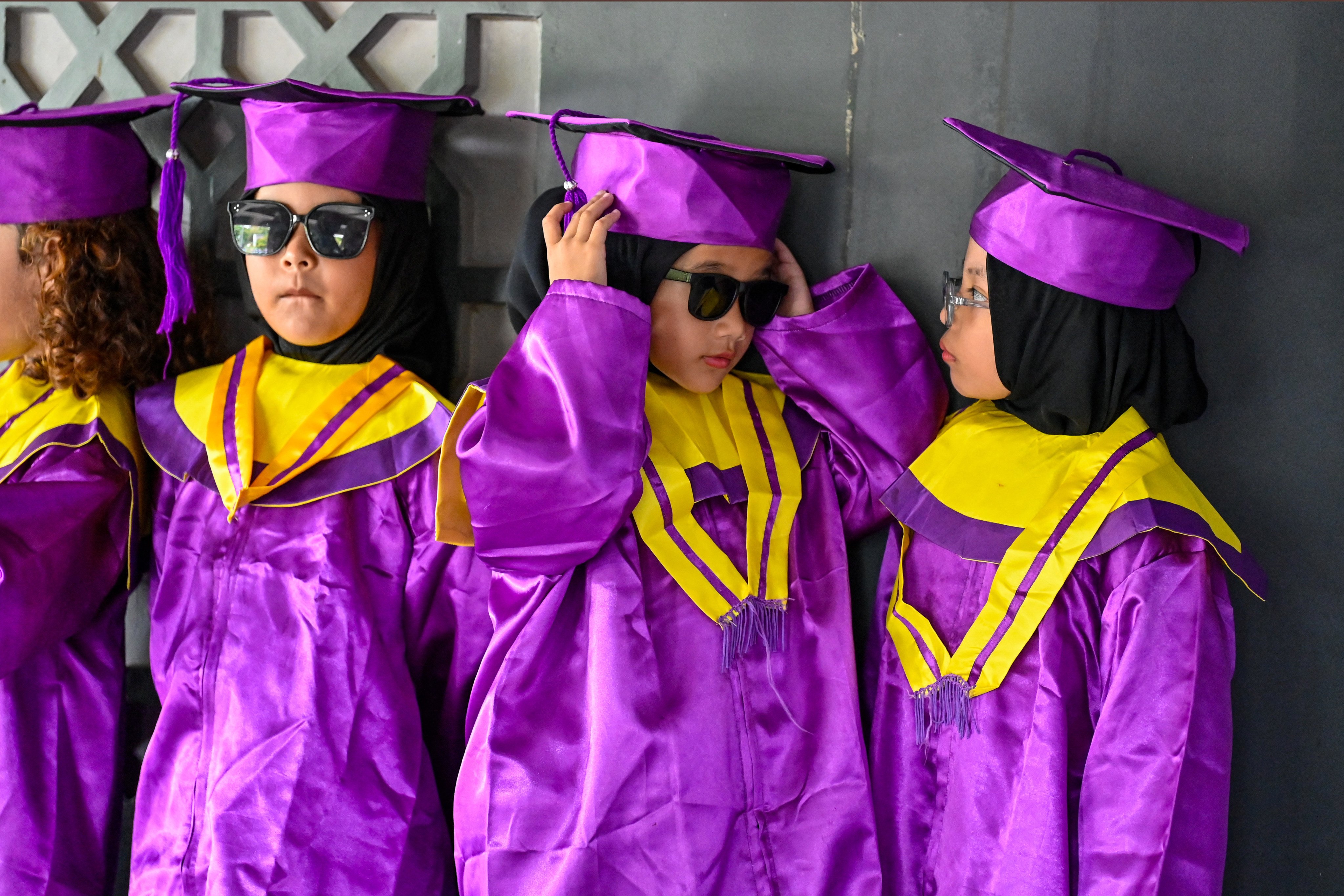 Kindergarteners wearing graduation gowns wait to have their photographs taken at a museum in Banda Aceh, Indonesia, in May. Photo: AFP