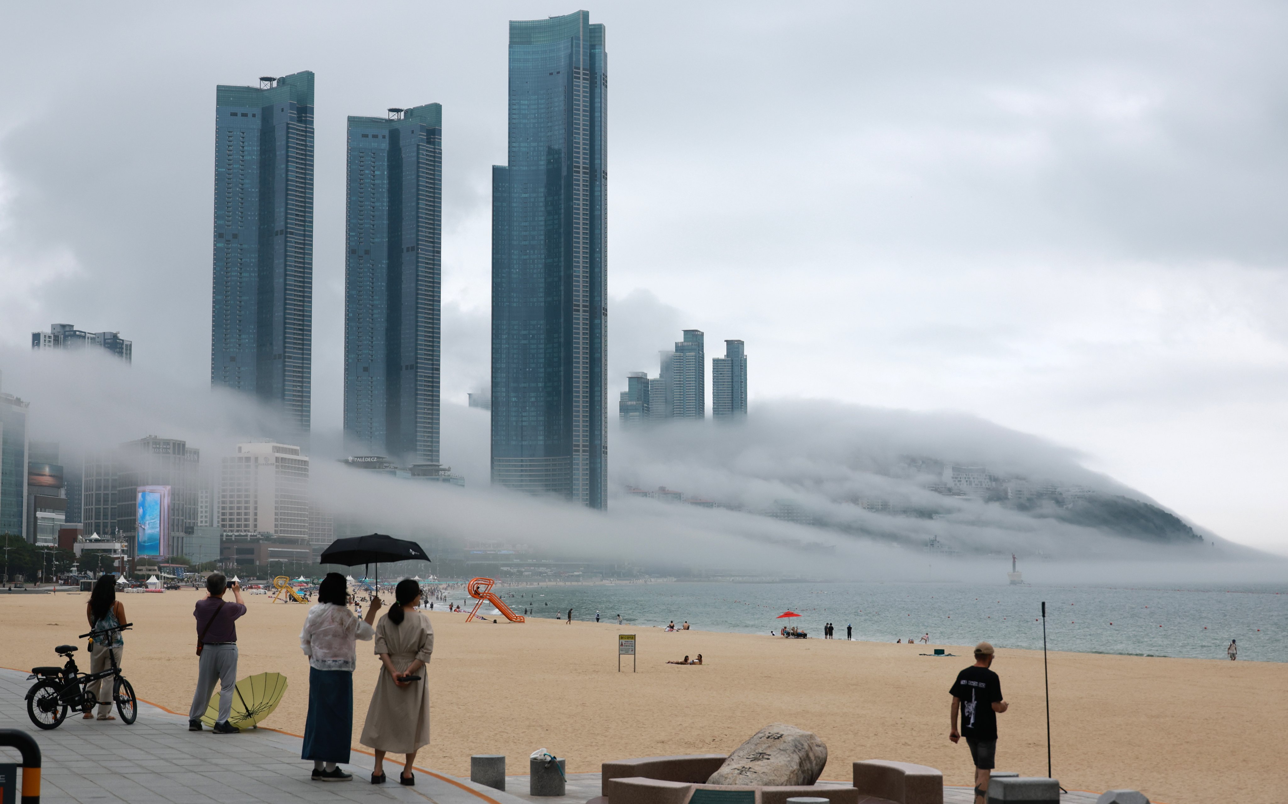 People watch sea fog spreading over Haeundae Beach in Busan on July 7. Photo: Yonhap/EPA