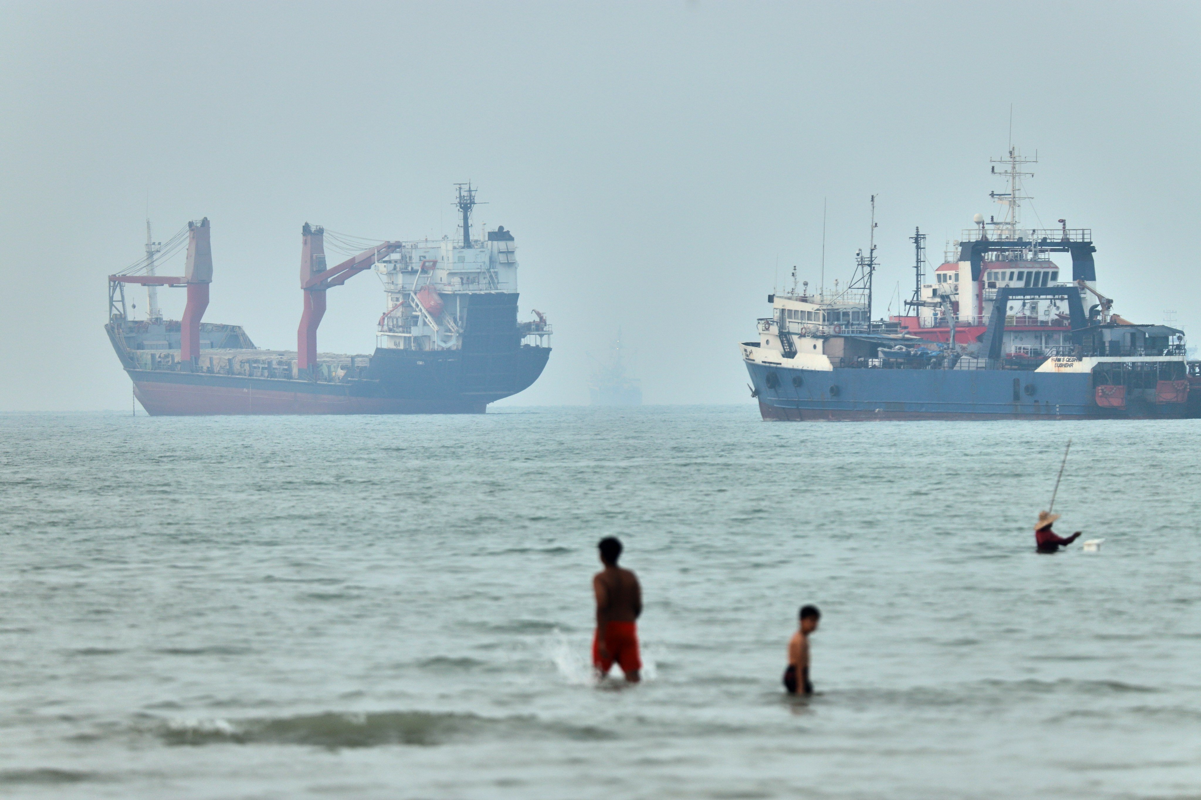 Onlookers wade in the Strait of Hormuz as ships wait to leave. Photo: ISNA via AP