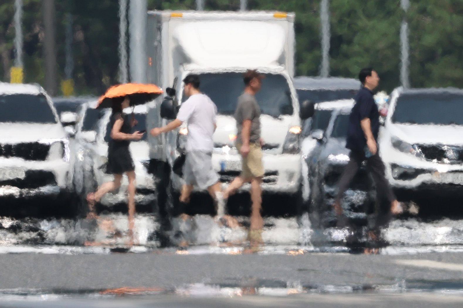 The air shimmers over a road in Seoul’s Yeongdeungpo ward, as people walk along a pedestrian crossing on a hot day. A heat warning has been issued for Seoul. Photo: dpa