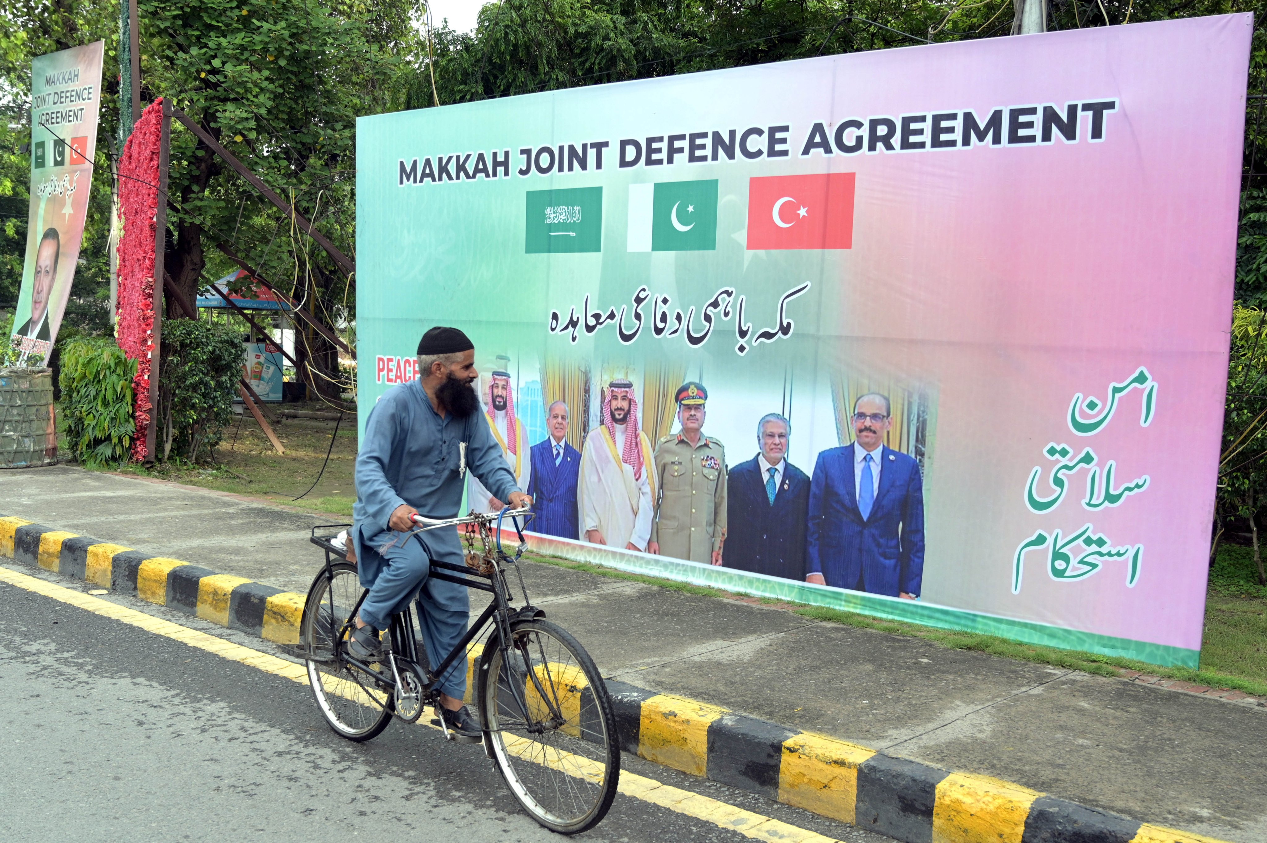 A man rides past a hoarding celebrating the signing of the Mecca defence deal in Lahore on Sunday. Photo: EPA