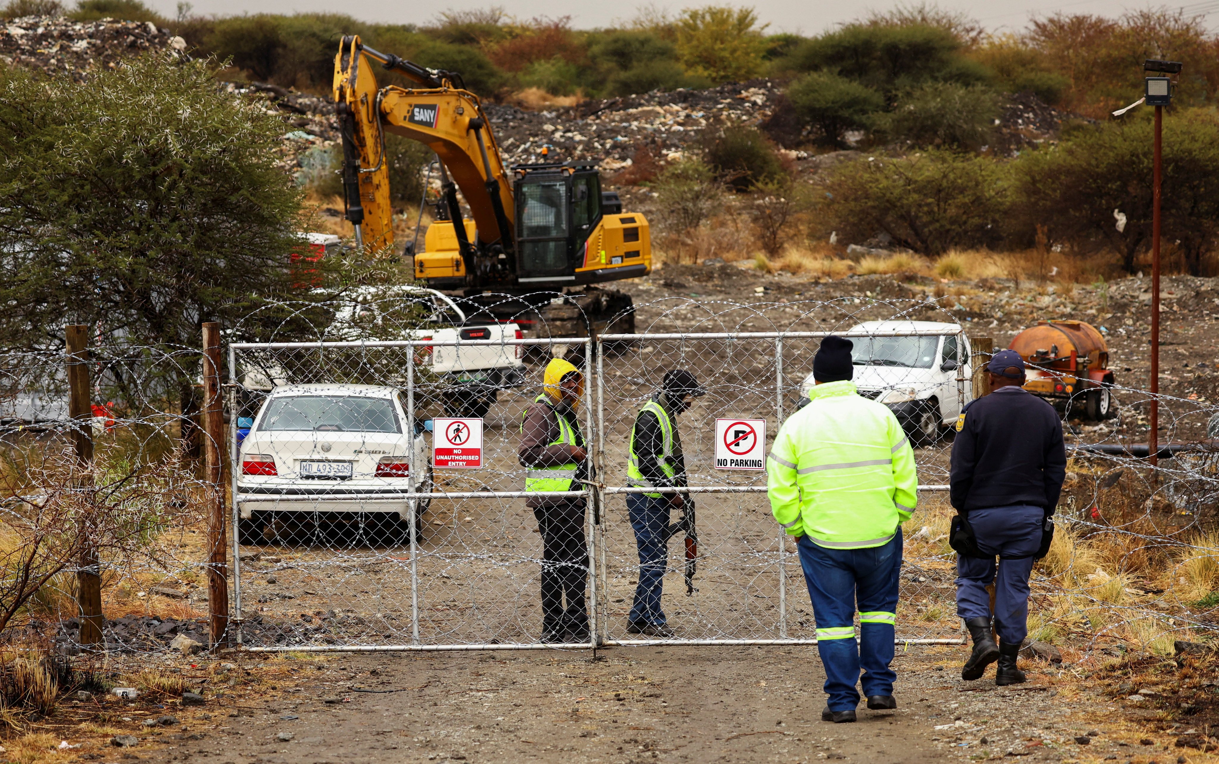 A police officer interacts with security at the gate of a disused mine near Rustenburg, North West province, South Africa. Police say 14 illegal miners were killed and others injured at the disused mine on Monday. Photo: Reuters