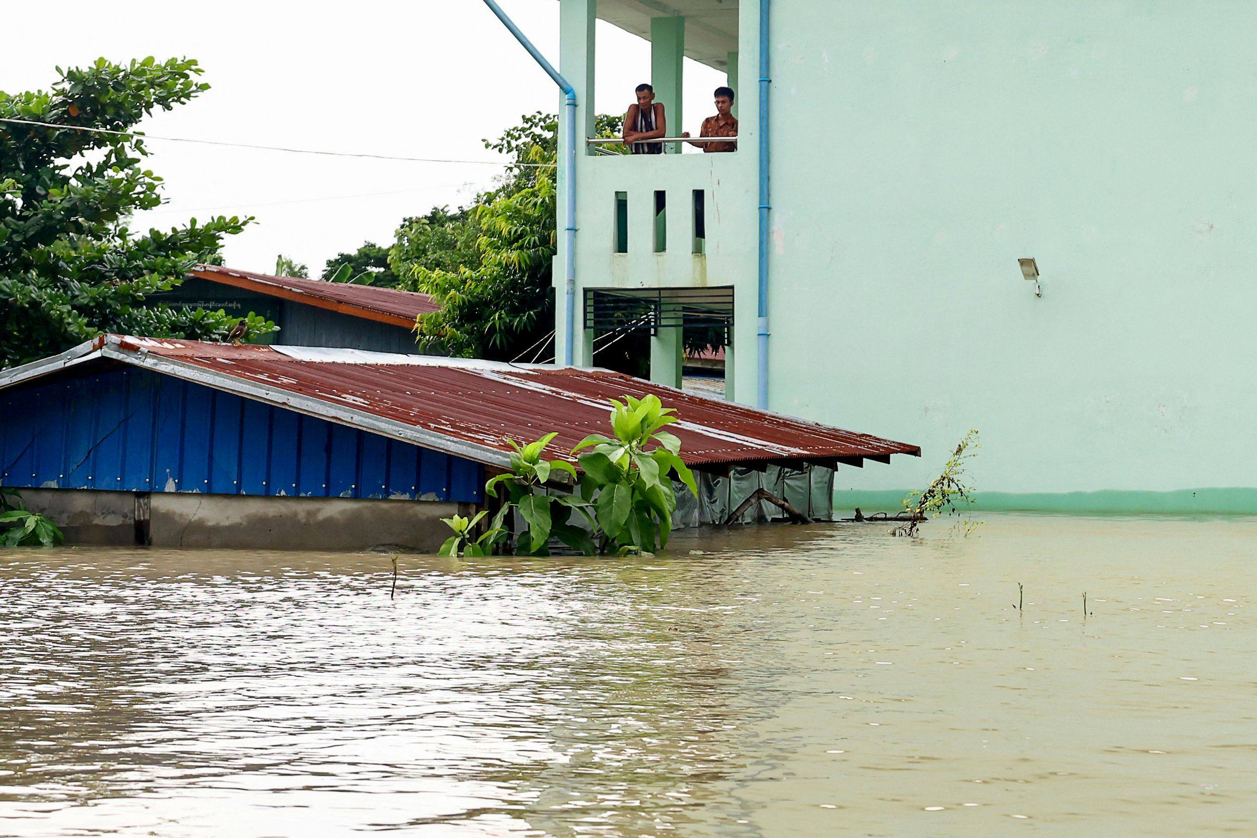 Residents look out at flood waters from a building in Lemyethna in Myanmar’s Irrawaddy Delta region on August 3. Photo: AFP