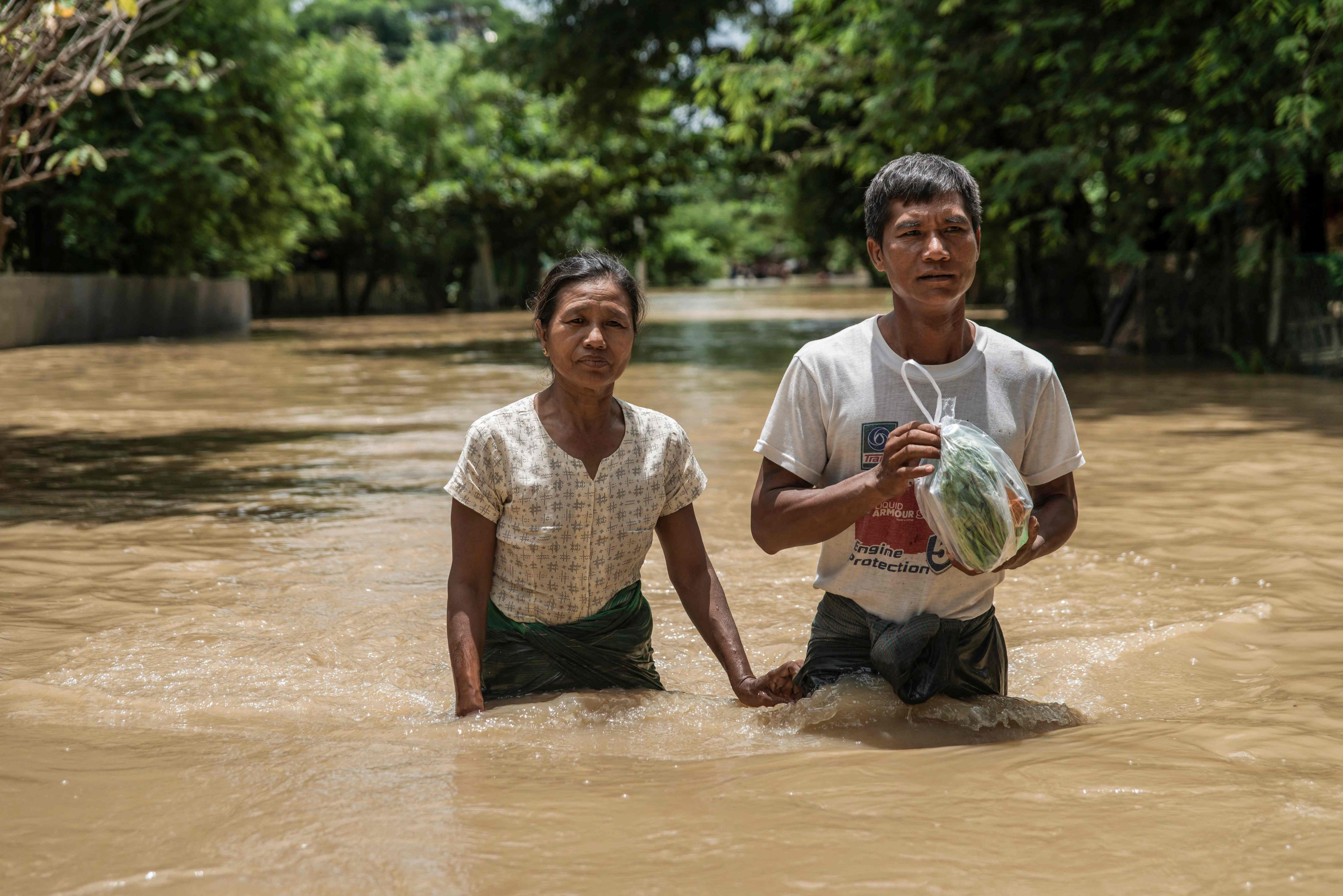 People wade through a flooded area due to monsoon rains and rising river water levels in Wetlet, Myanmar’s Sagaing region on Monday. Photo: AFP