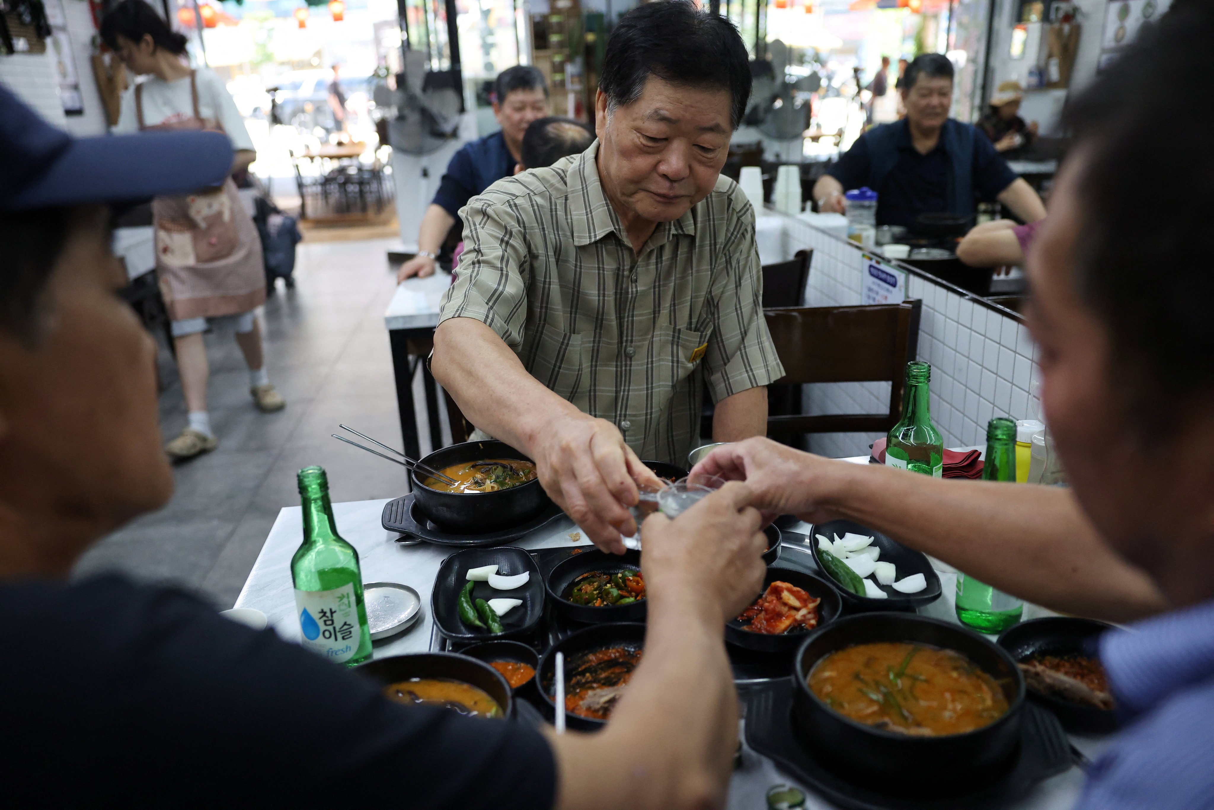 South Koreans toast as they eat dog meat stews during Malbok, the last of Korea’s traditional hottest days of summer, at a restaurant selling dog meat and black goat meat stews in Seongnam, South Korea on Friday. Photo: Reuters