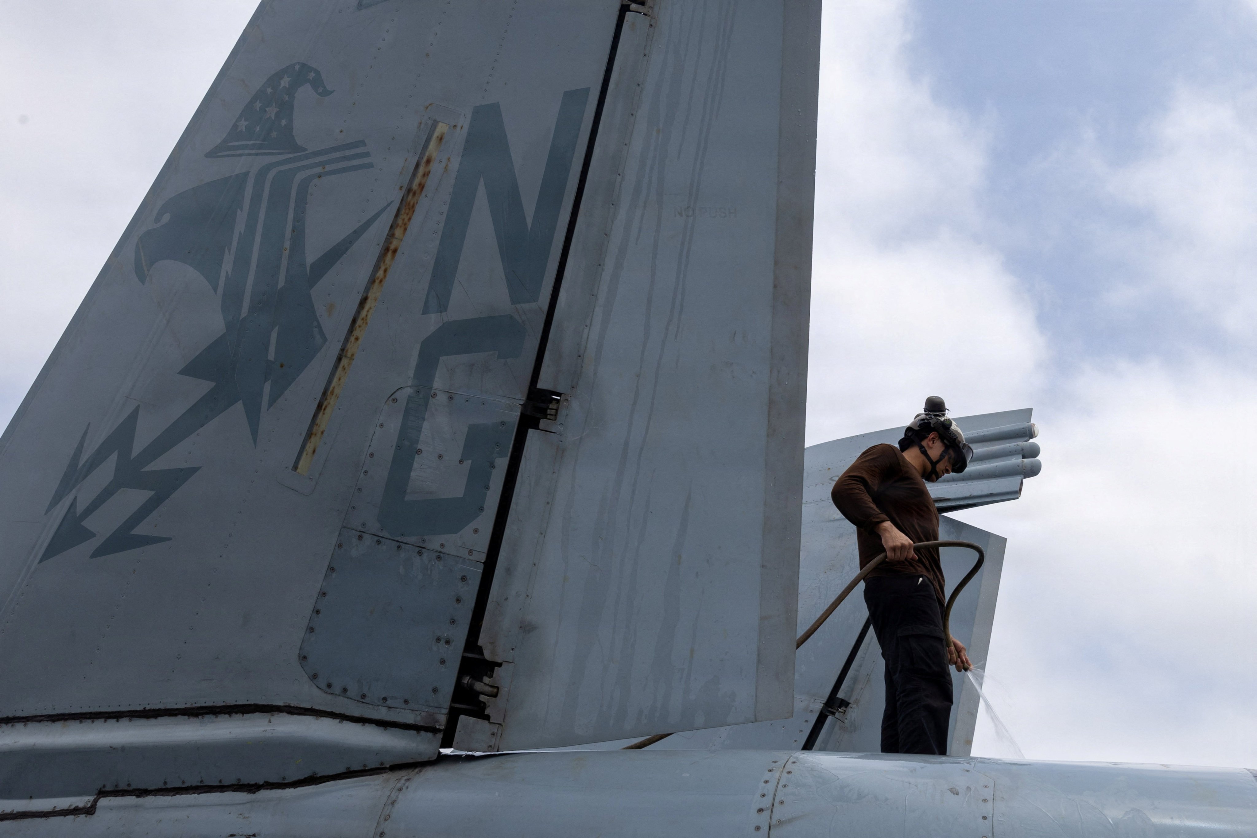 A U. sailor washes an EA-18G Growler on the flight deck of the USS Abraham Lincoln on August 9. Photo: US Navy/Reuters
