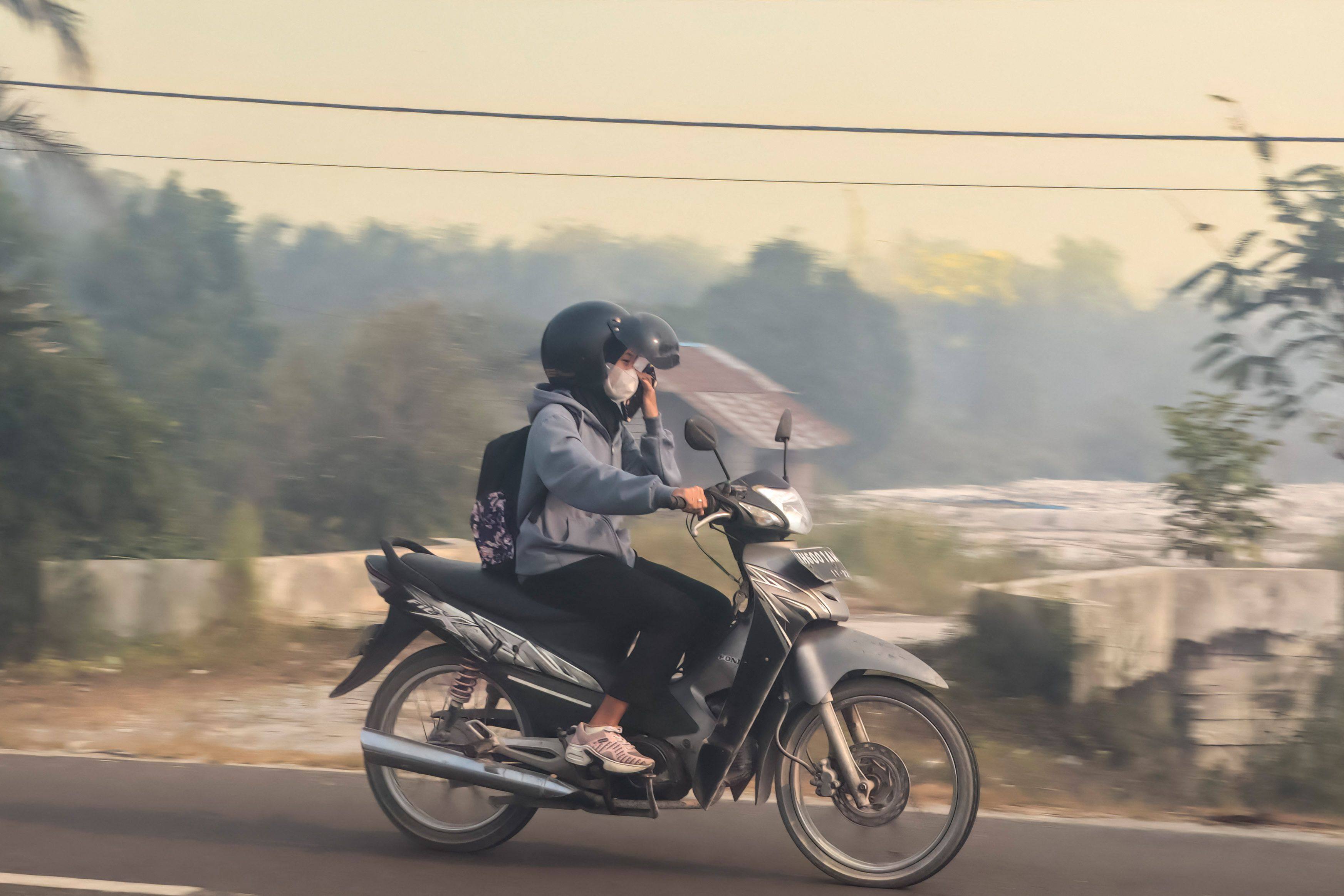 A resident wearing a face mask rides a motorbike on a haze-shrouded road in Palangka Raya city, central Kalimantan on Thursday. Photo: AFP