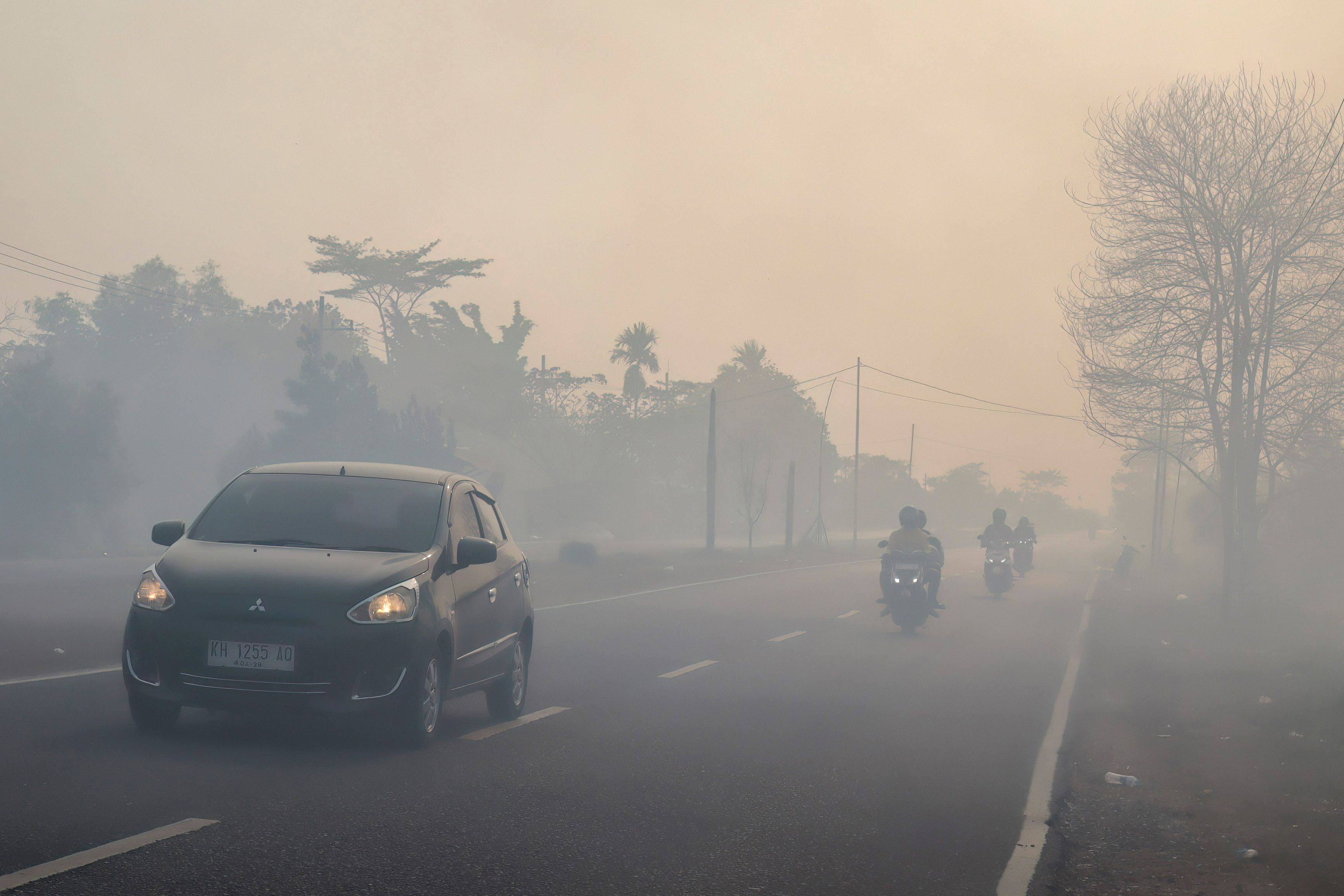 Motorists drive on a haze-shrouded road in Palangka Raya city, central Kalimantan on Thursday. Photo: AFP