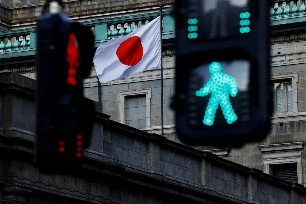 FILE PHOTO: Japanese national flag hoisted atop of the Bank of Japan headquarters building is seen between traffic signals in Tokyo, Japan January 23, 2025. REUTERS/Issei Kato/File Photo