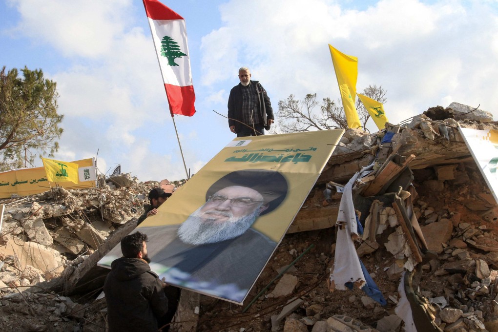 People place a picture of Hezbollah leader Hassan Nasrallah over the rubble of the shrine of Shamoun al-Safa in southern Lebanon’s Tyre region on Friday. Nasarallah was killed on September 27 after a series of Israeli airstrikes in Beirut. Photo: AFP