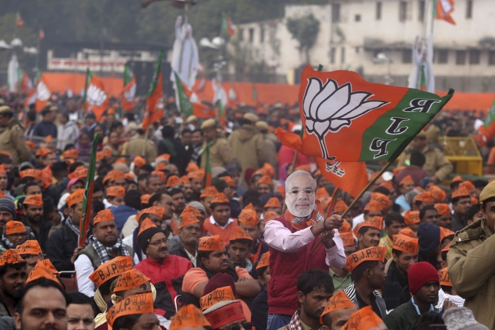 A man wearing a mask of Indian Prime Minister Narendra Modi waves a flag of his Hindu nationalist Bharatiya Janata Party during a rally in New Delhi, India. Photo: AP
