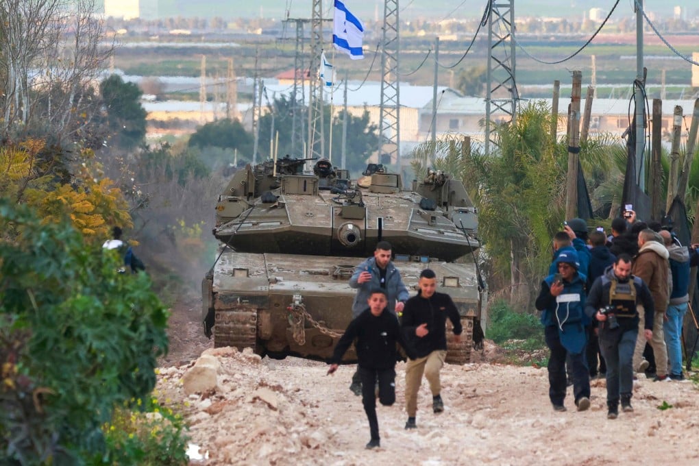 Palestinian children and journalists disperse as Israeli tanks enter the Jenin camp for Palestinian refugees. Photo: AFP