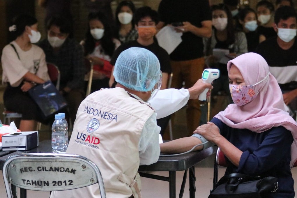 USAID health worker performs a routine health assessment before administering the COVID-19 vaccine to the patient at a mass vaccination clinic in Indonesia in 2021. Photo: USAID