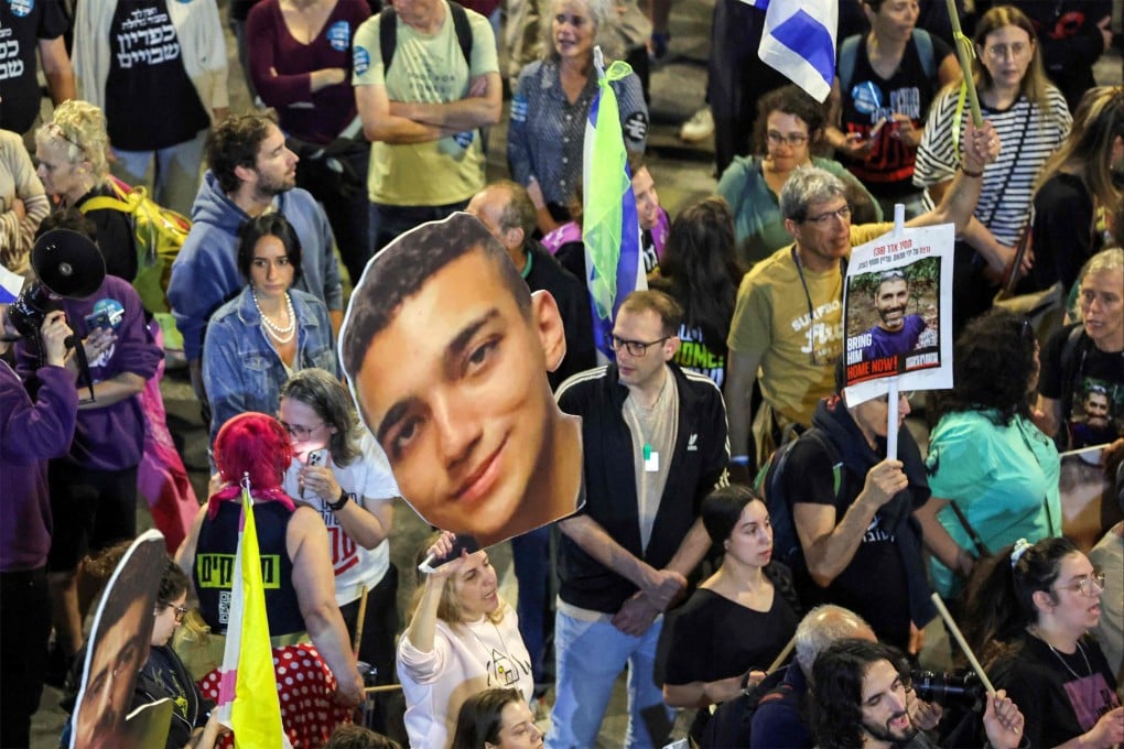 Demonstrator holds a sign showing the face of Israeli hostage Edan Alexander, centre, during a protest calling for action to release the remaining hostages held captive in Gaza, outside the Israeli Defence Ministry headquarters in Tel Aviv on Saturday. Photo: AFP