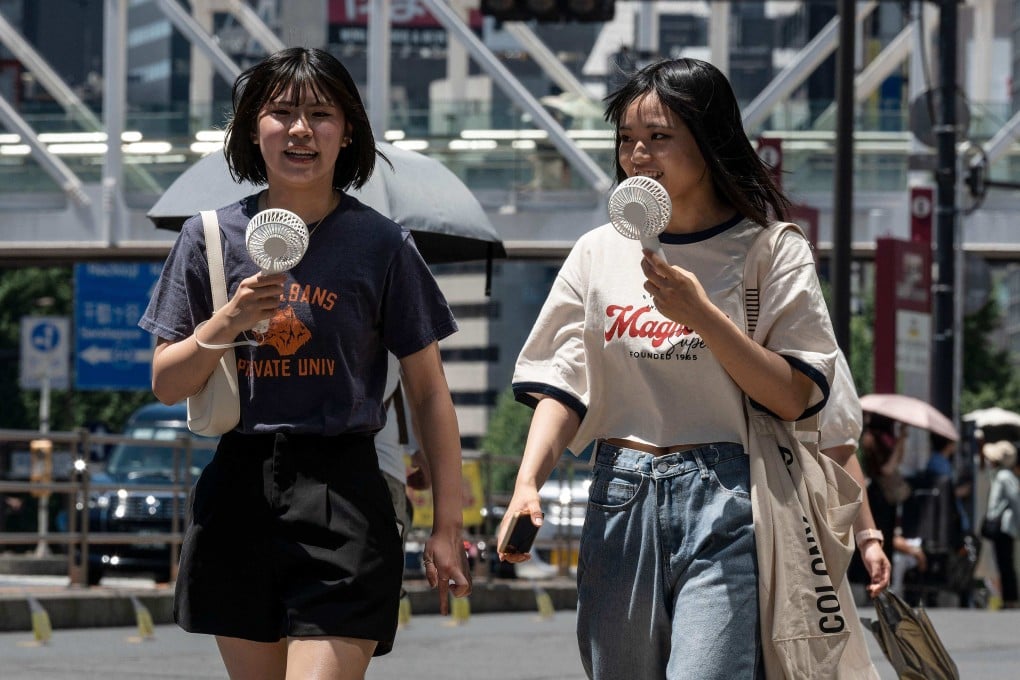 Young women use fans to seek relief from the heat in Tokyo. Japan’s weather agency says the country could face annual once-in-a-century heatwaves if global warming continues. Photo: AFP