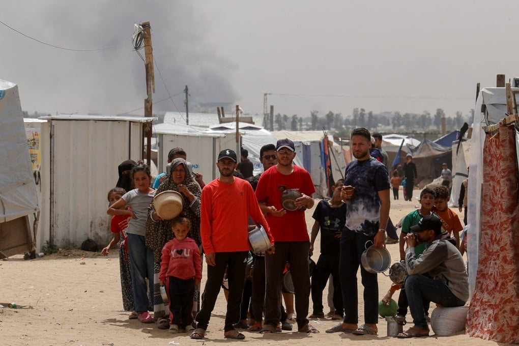 Smoke rises from an Israeli strike as Palestinians wait to receive food cooked by a charity kitchen, in Khan Younis, southern Gaza on Sunday. Photo: Reuters
