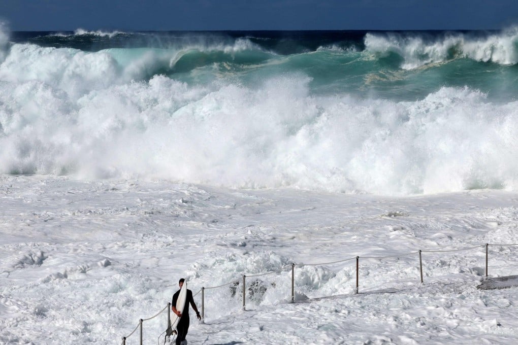 A surfer is dwarfed by large wave on Bronte Beach in Sydney on Friday as powerful swells hit Australia’s east coast. Photo: AFP